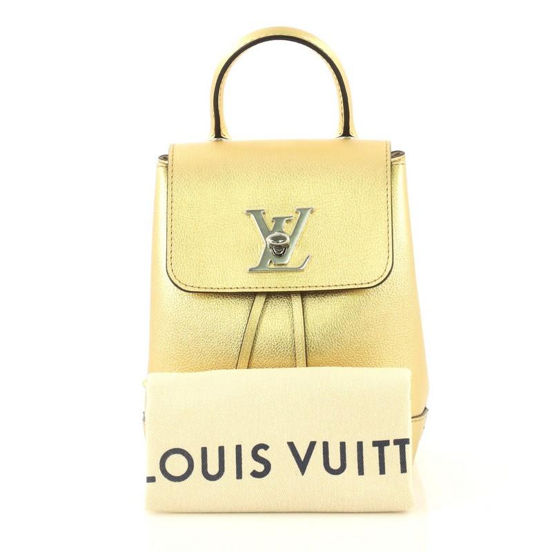 This Louis Vuitton Lockme Backpack Leather Mini, crafted in metallic gold leather, features a leather top handle, adjustable shoulder straps, and silver-tone hardware. Its turn-lock and drawstring closure opens to a neutral microfiber interior with