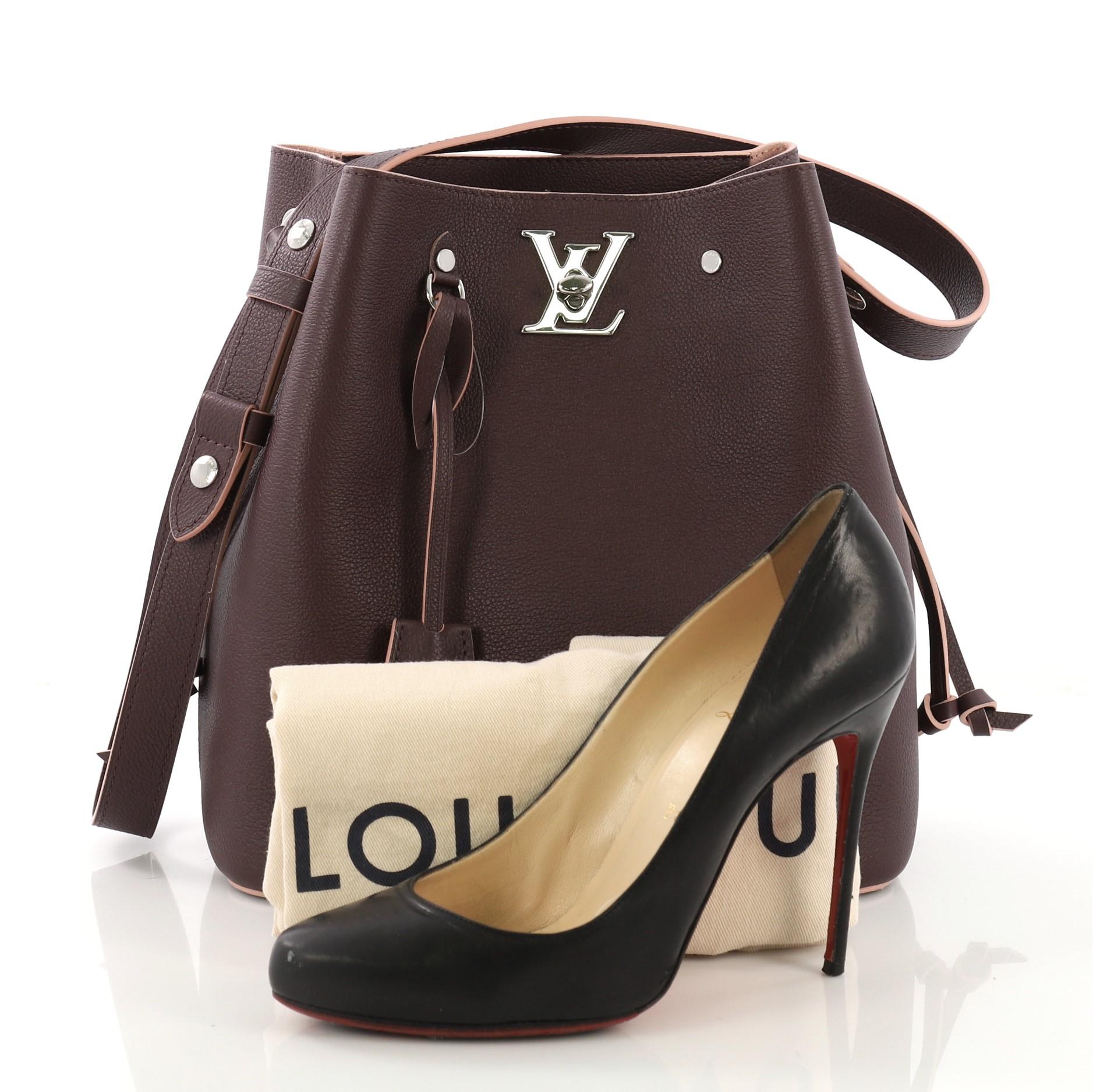 This Louis Vuitton Lockme Bucket Bag Leather, crafted in burgundy leather, features a leather shoulder strap, leather thread that cinches the bag, and gunmetal-tone hardware. Its LV turn-lock closure opens to a light pink microfiber interior with