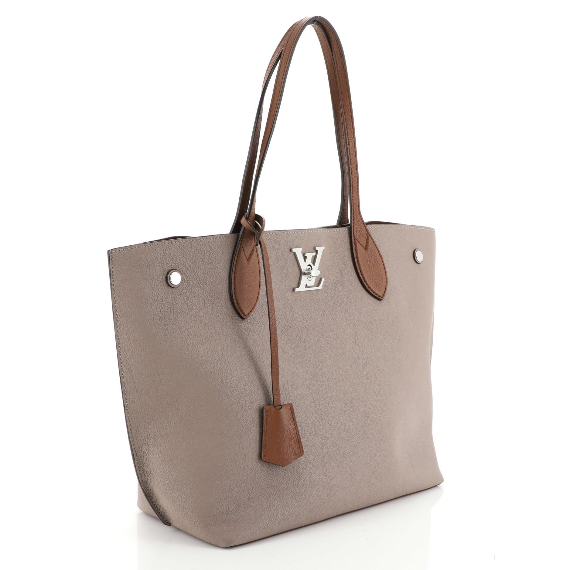 This Louis Vuitton Lockme Go Tote Leather, crafted from brown leather, features dual flat leather handles, LV twist closure, and silver-tone hardware accents. Its turn-lock closure opens to a brown microfiber interior with zip and slip pockets.