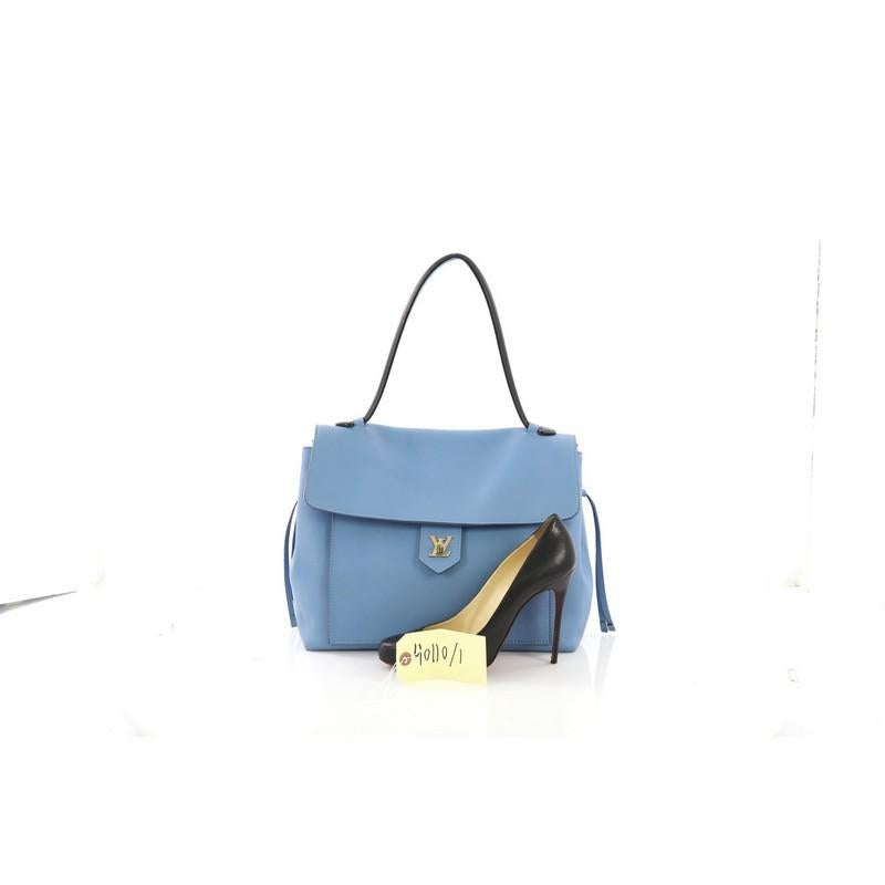 This Louis Vuitton Lockme Handbag Leather MM, crafted in light blue leather, features a single loop leather handle, side laces that cinch the bag, slip pocket under flap, and gold-tone hardware. Its flap with turn-lock closure opens to a light blue