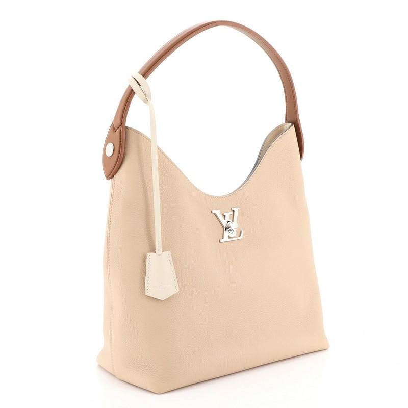 This Louis Vuitton Lockme Hobo Leather, crafted from neutral leather, features leather top handle and silver-tone hardware. Its LV turn lock closure opens to a neutral microfiber interior with slip pockets. Authenticity code reads: AR5128.