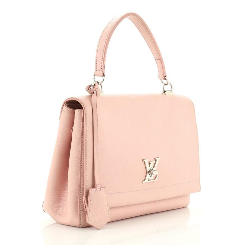 This Louis Vuitton Lockme II Handbag Leather, crafted from pink leather, features a single loop leather handle, side snap buttons, and silver-tone hardware. Its LV turn-lock closure opens to a pink fabric interior with slip pockets. Authenticity