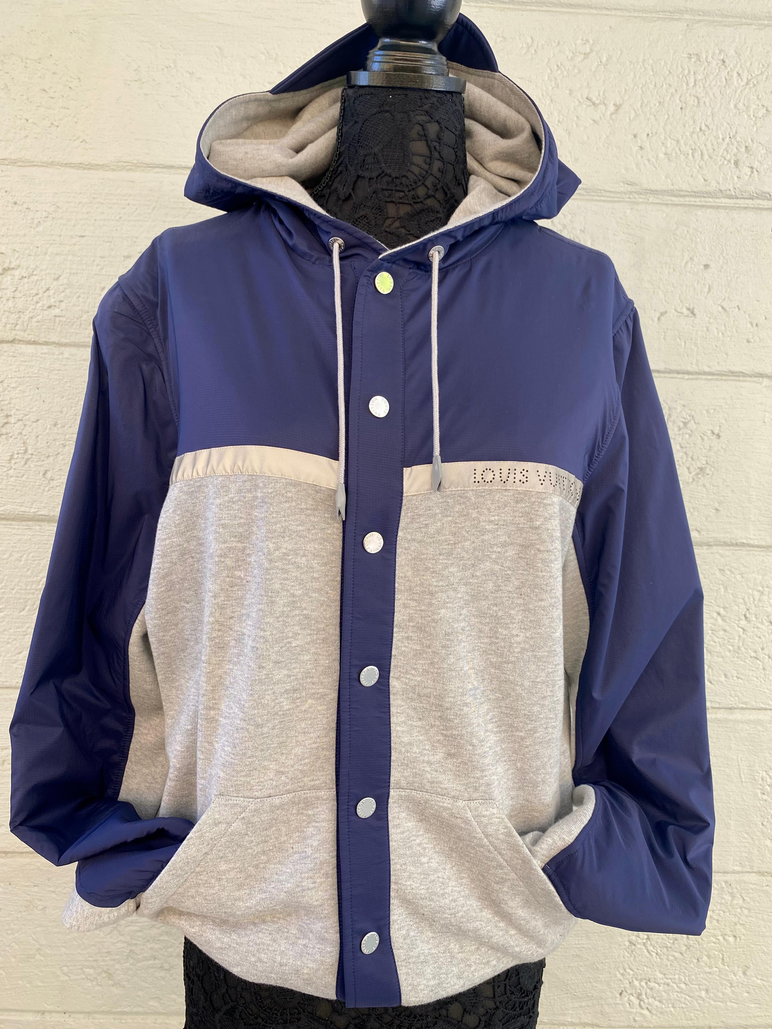 Tailored from a comfortable technical cotton jersey, this iconic button up travel hoodie features a metallic silver reflective Louis Vuitton logo perforated signature. Beautiful navy blue and gray color combination. 
This Louis Vuitton jacket is the