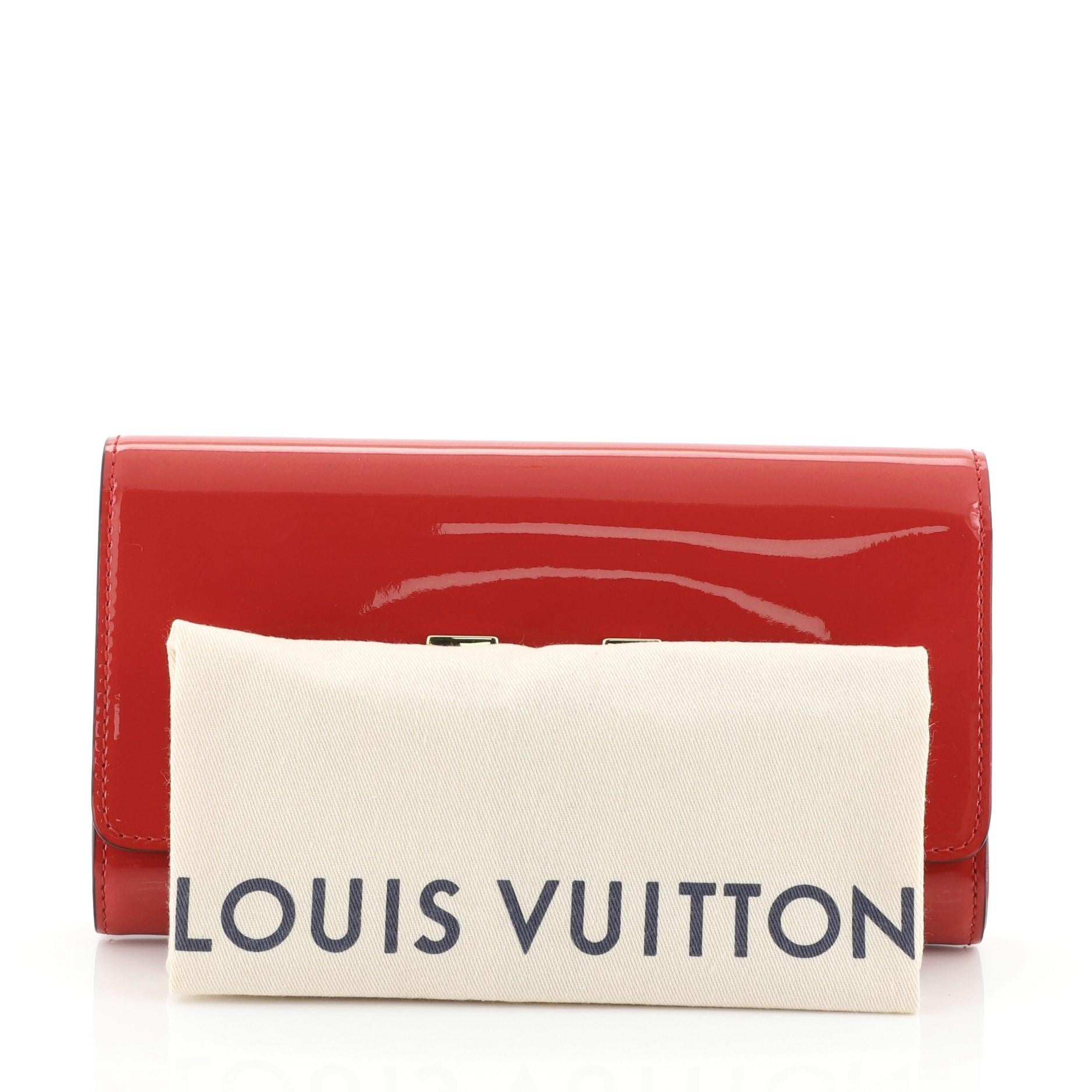 This Louis Vuitton Louise Clutch Patent East West, crafted in red leather, features an oversized LV logo flip lock and gold-tone hardware. Its flap with flip lock closure opens to a red fabric interior with zip and slip pockets. Authenticity code