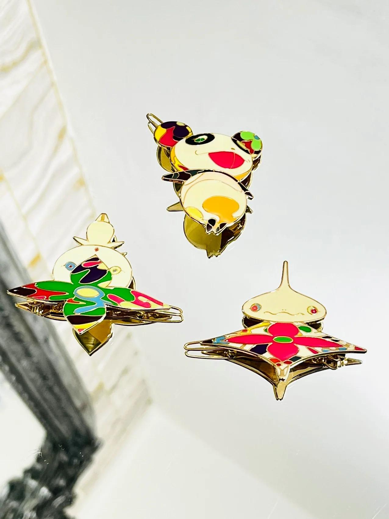 Louis Vuitton Ltd Edition Takashi Murakami Collection Hair Clips

Set of 3 brass and enamel Louis Vuitton hair barrettes with monogram accents throughout and hinged clasp closure at back.

Additional information:
Size – O/S
Composition – Brass,
