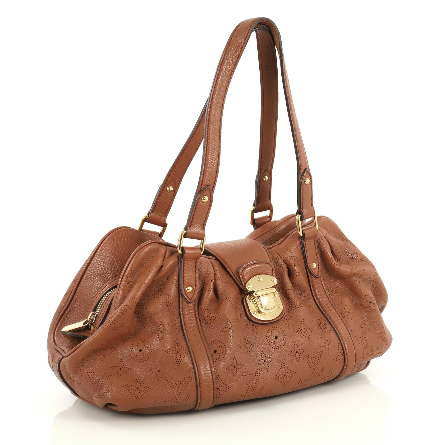 This Louis Vuitton Lunar Handbag Mahina Leather PM, crafted from brown monogram perforated mahina leather, features dual flat tall handles, protective base studs, top flap push-lock closure and gold-tone hardware. Its zip closure opens to a brown