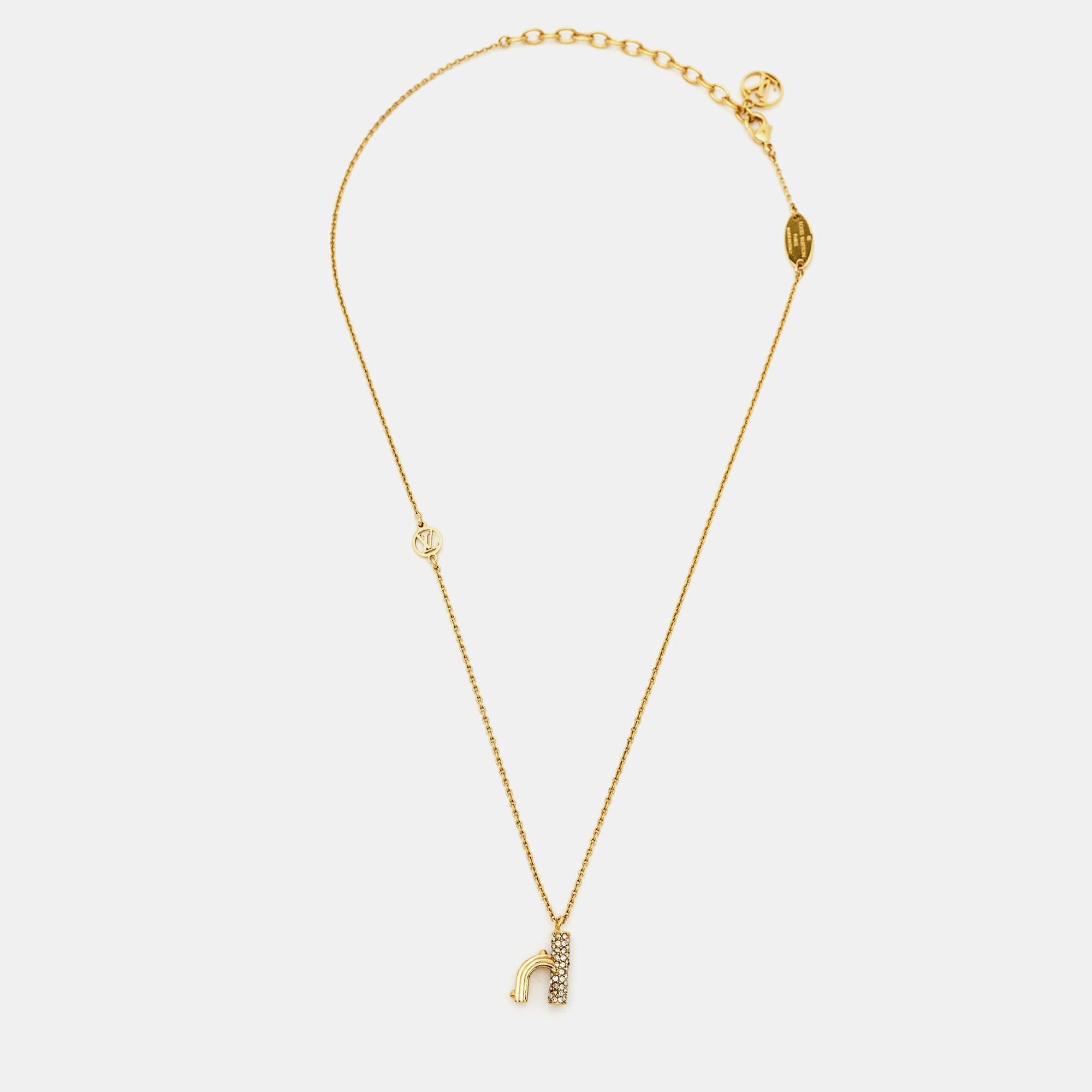 The Louis Vuitton LV & Me necklace is a luxurious fashion accessory. It features a gold-tone chain adorned with sparkling crystals and a pendant in the shape of the letter 