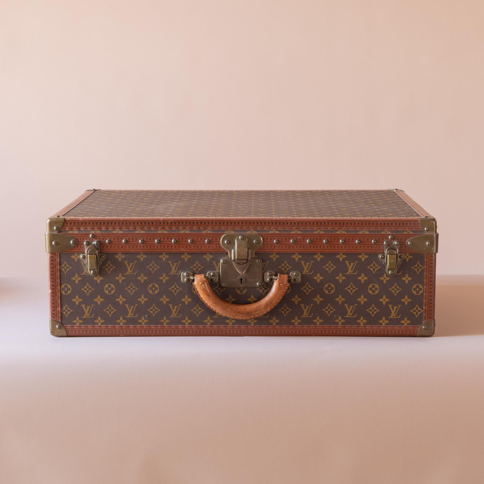 Louis Vuitton large ‘Alzer’ suitcase in LV monogram pattern coated canvas with edges trimmed in lozine and unpolished brass fittings. The lid of the case is secured by a central sprung catch with lock, plus two additional latches. Cream coated