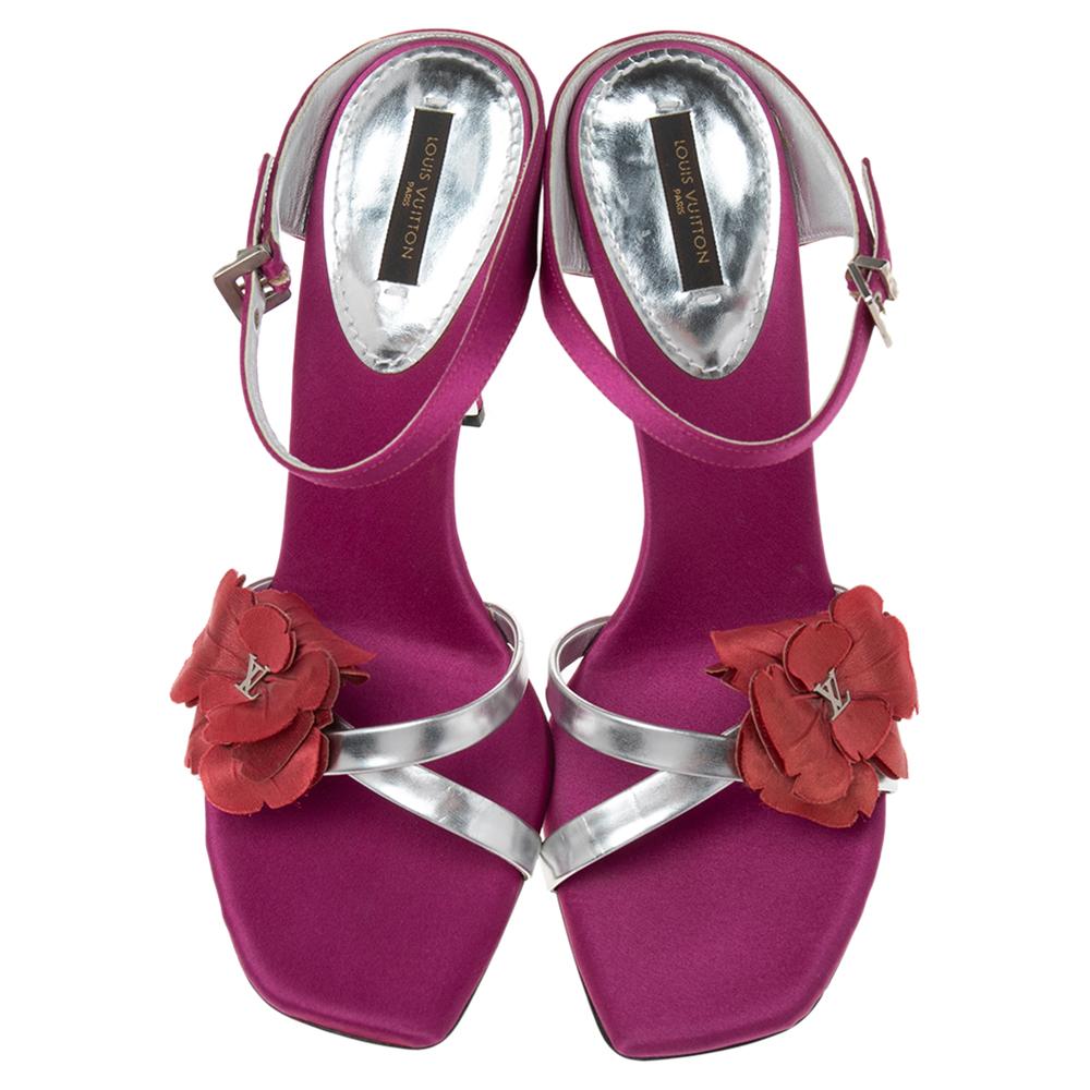 How beautiful are these sandals from Louis Vuitton! They are fashioned in magenta-silver satin and leather, with a delicate floral applique attached to their upper. These sandals come with an ankle strap, silver-toned hardware, and pointy heels. Amp