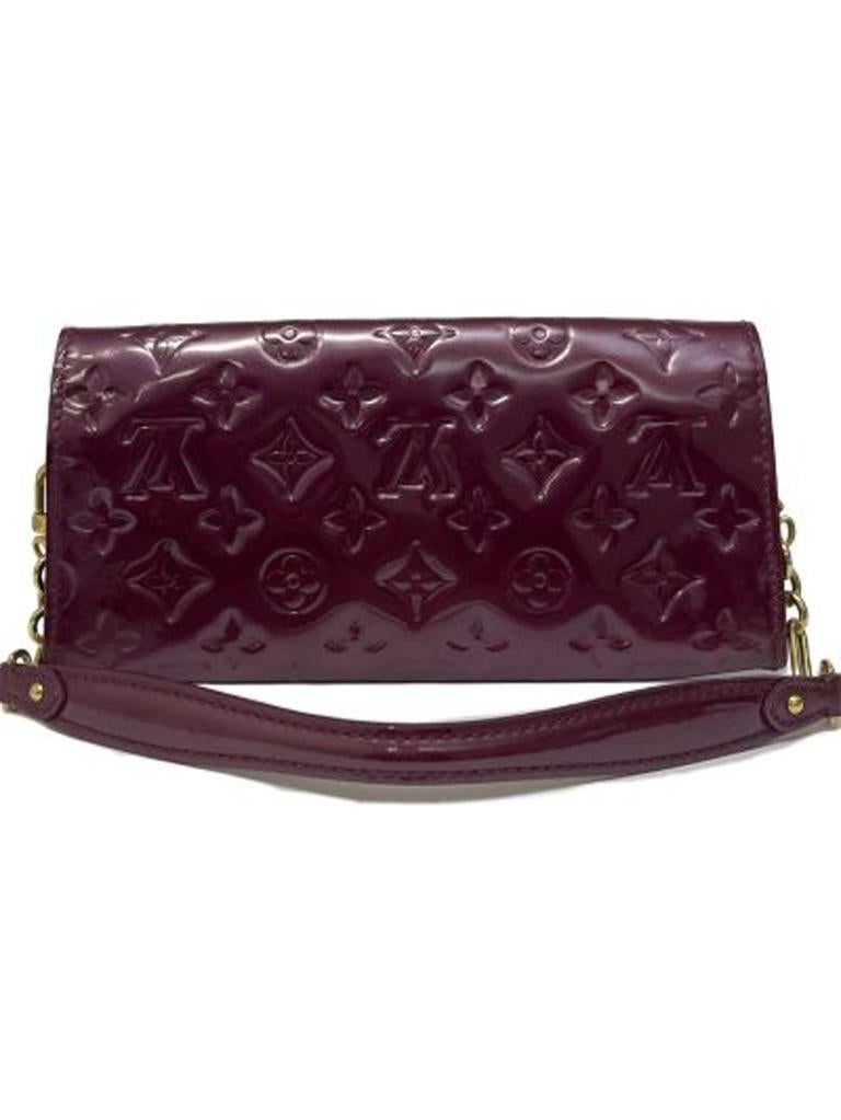 Louis Vuitton signature clutch bag, made in magenta paint, with gold hardware.The product is equipped with a button closure, internally lined in fabric and leather, roomy for the essentials.There is also a removable patent and chain handle, and
