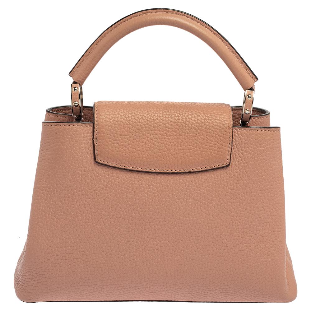 It is every woman's dream to own a Louis Vuitton handbag as appealing as this one. Crafted from Taurillon leather, this bag features a structured design with a single handle and protective metal feet. While the front LV elevates its beauty, the