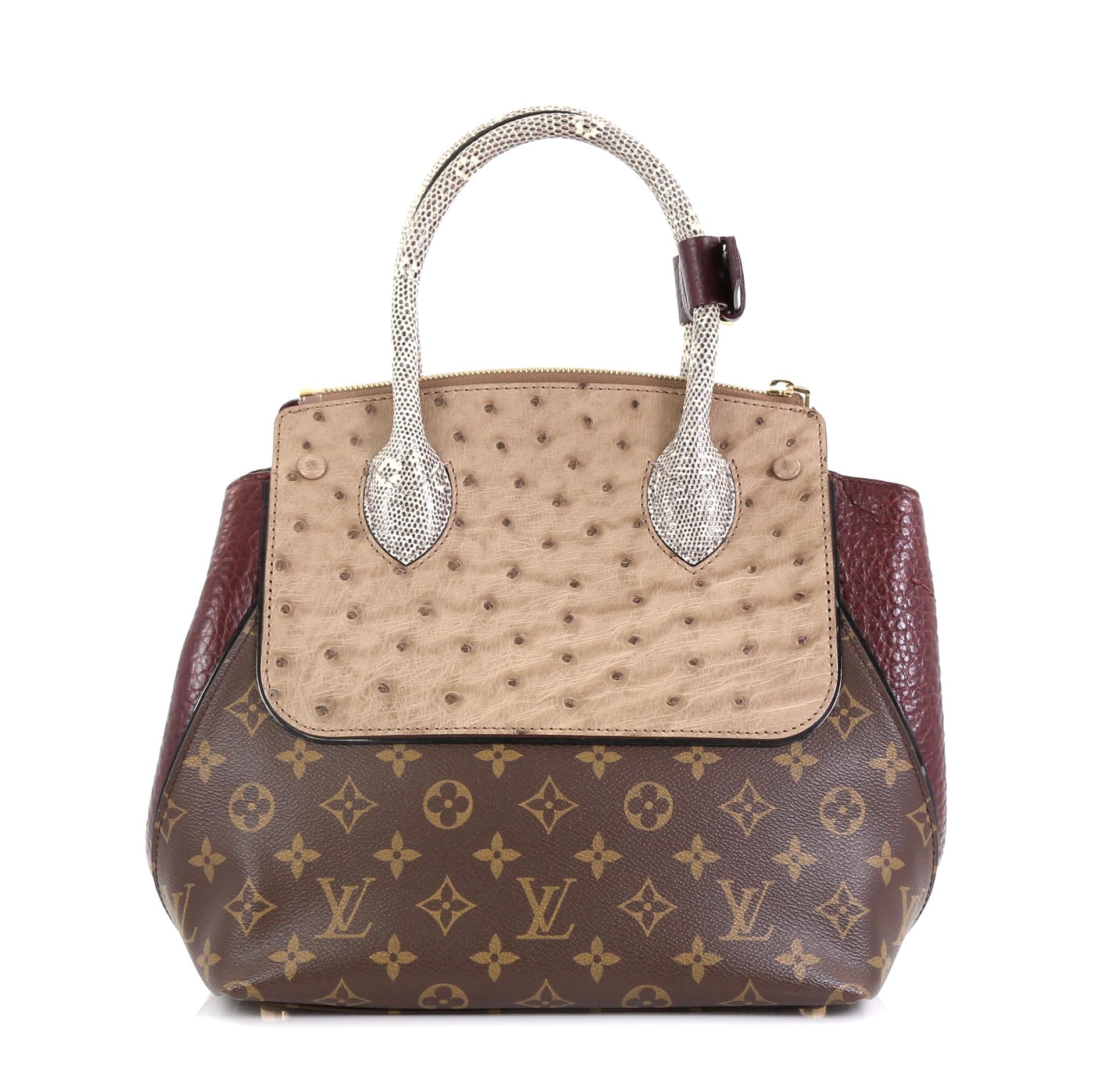 This Louis Vuitton Majestueux Tote Monogram Canvas and Exotics PM, crafted in brown monogram coated canvas and exotics, features dual rolled handles, protective base studs, and gold-tone hardware. Its S-lock and zip closure opens to a red leather