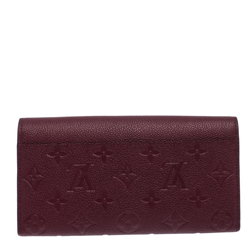 One of the most famous wallets by Louis Vuitton is Sarah. This one here comes made from Monogram Empreinte leather and the button on the flap opens to an interior with multiple card slots and a zip pocket. Perfect in size, this wallet can easily fit