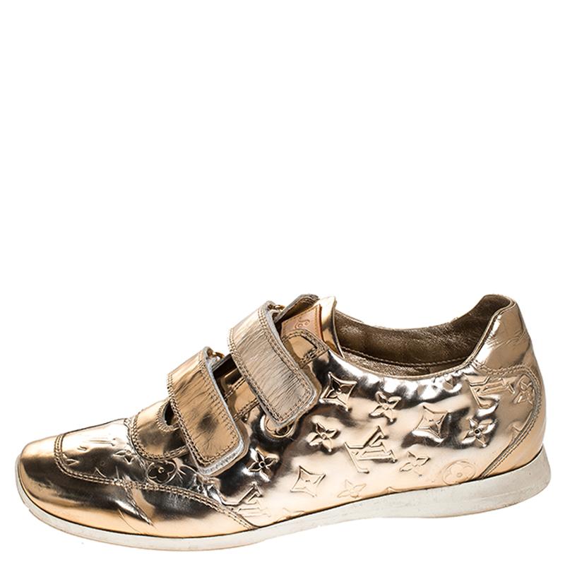 This unique pair of shoes from Louis Vuitton is all you need to bring out your style. Crafted from patent leather, they have a striking metallic gold hue and feature the brand's signature Monogram. They have velcro strap on the uppers,