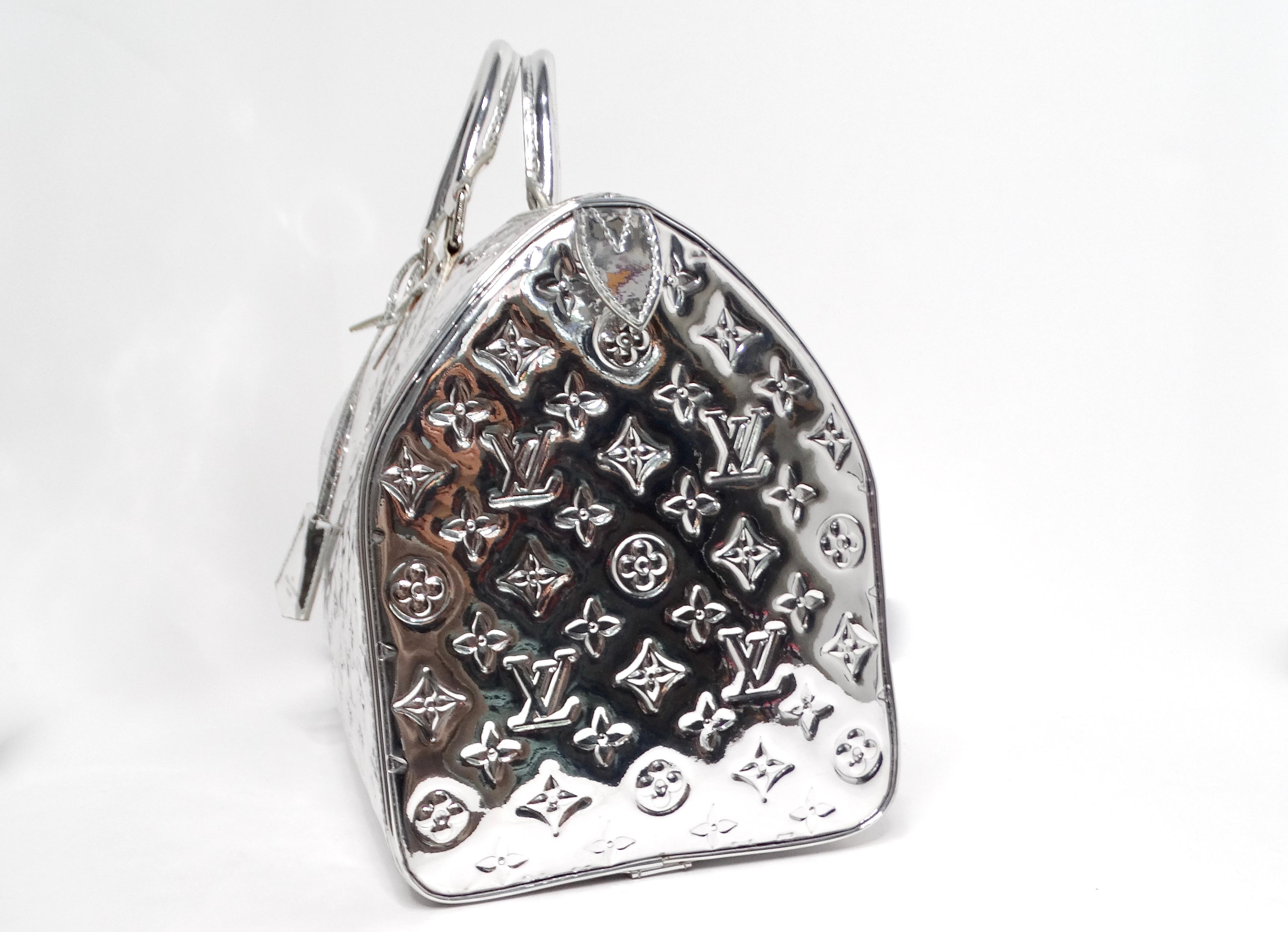 The Louis Vuitton Metallic Silver Monogram Miroir Speedy Duffle Bag is a statement piece that elevates any ensemble with its distinctive metallic sheen and iconic monogram pattern. Crafted from patent leather, this bag seamlessly combines luxury