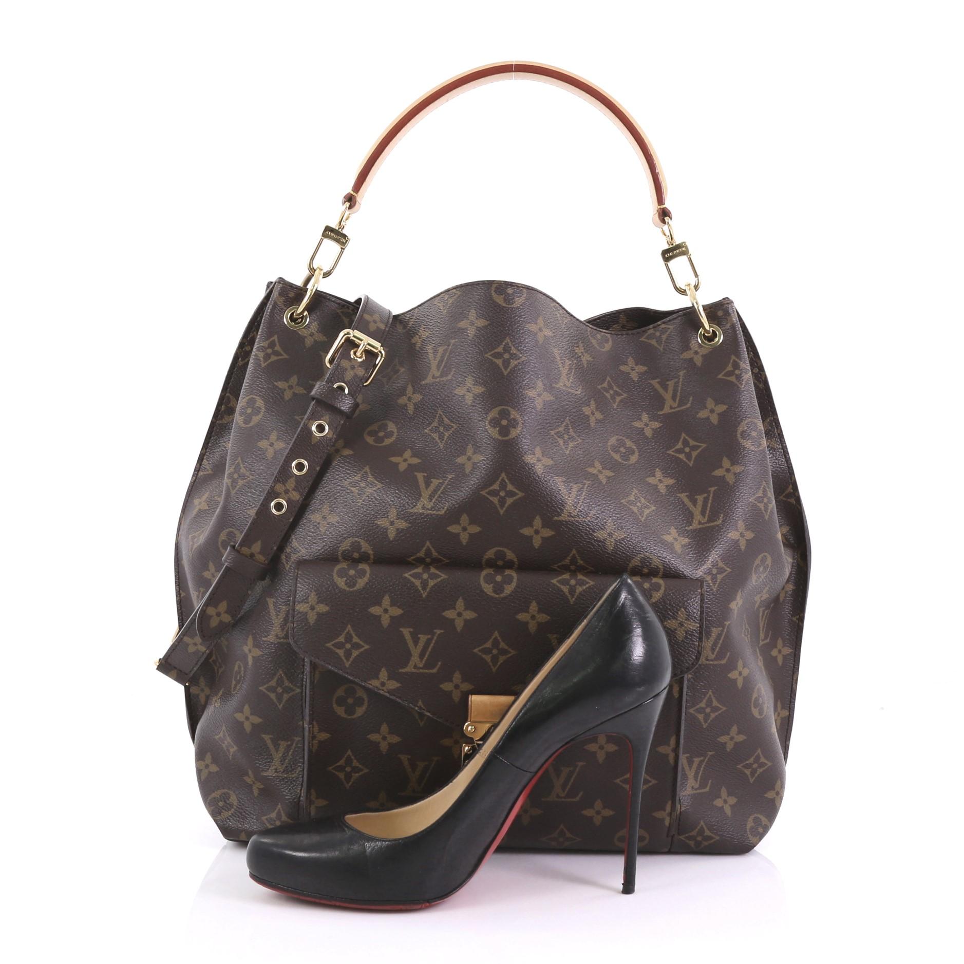 This Louis Vuitton Metis Hobo Monogram Canvas, crafted in brown monogram coated canvas, features front flap pocket with S-lock closure, removable vachetta leather handle, and gold-tone hardware. Its wide top opening showcases a brown microfiber