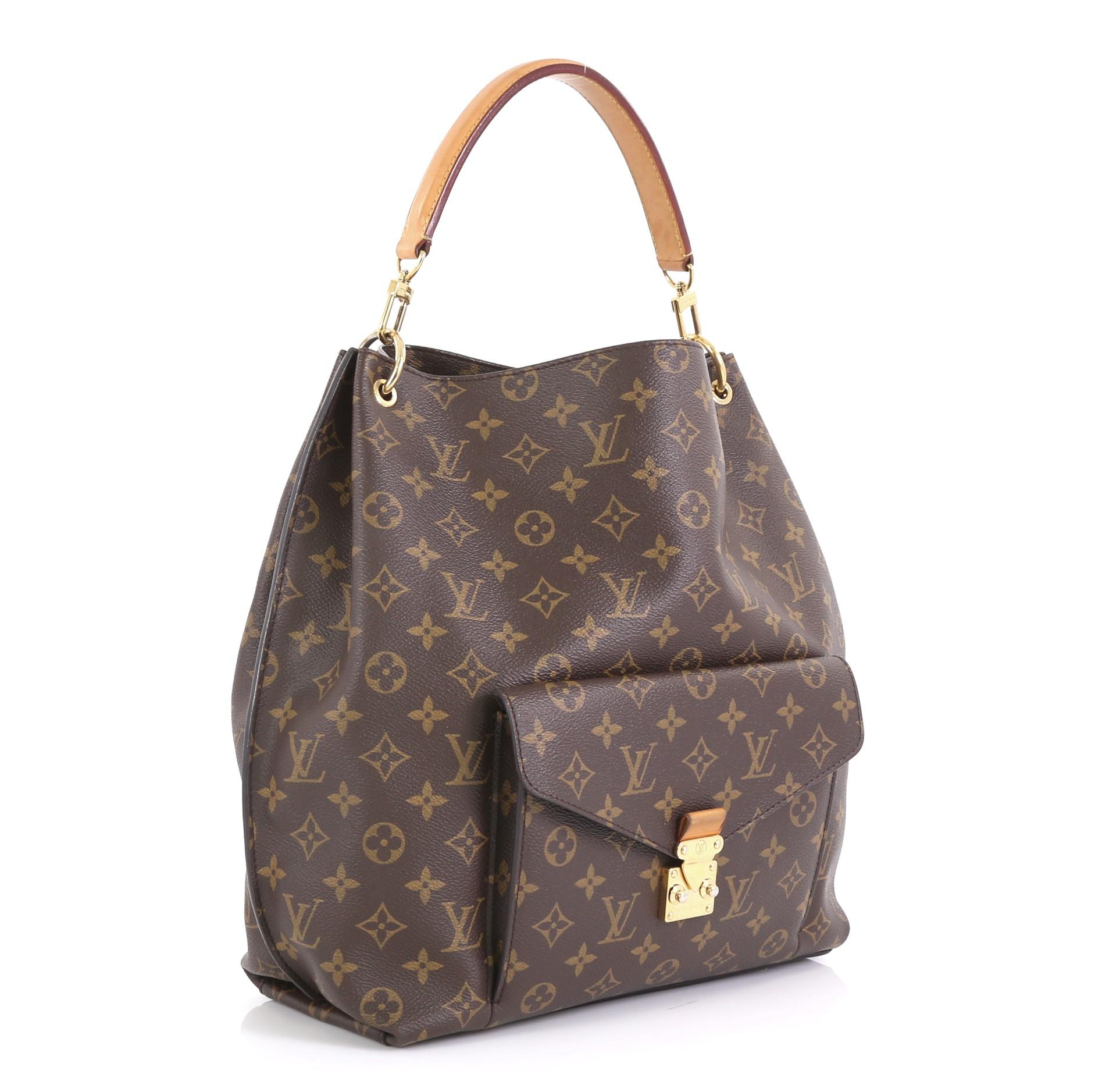 This Louis Vuitton Metis Hobo Monogram Canvas, crafted in brown monogram coated canvas, features vachetta leather handle, front flap pocket with S-lock closure, protective base studs and gold-tone hardware. Its wide top opening showcases brown