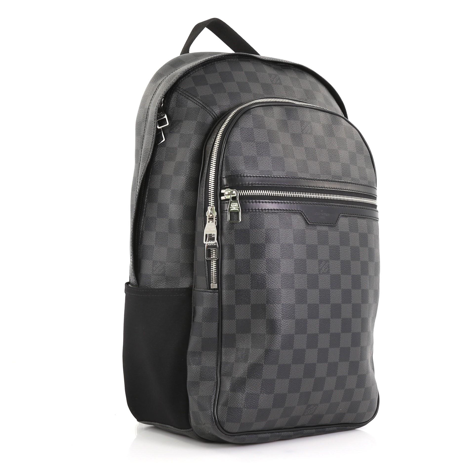 This Louis Vuitton Michael Backpack Damier Graphite, crafted from damier graphite coated canvas, features top leather handle, two canvas padded backpack straps, leather trim, two exterior front zip pockets, one compartment with slip pockets and