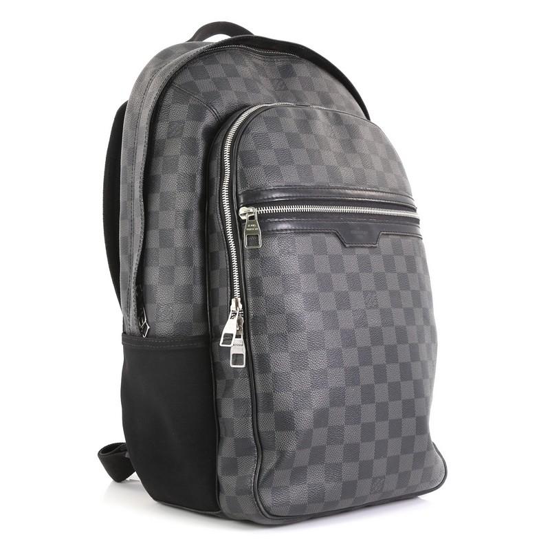 This Louis Vuitton Michael Backpack Damier Graphite, crafted from damier graphite coated canvas, features a short flat leather handle, canvas padded backpack straps, black leather trims, exterior front zip pockets, one compartment with slip pockets