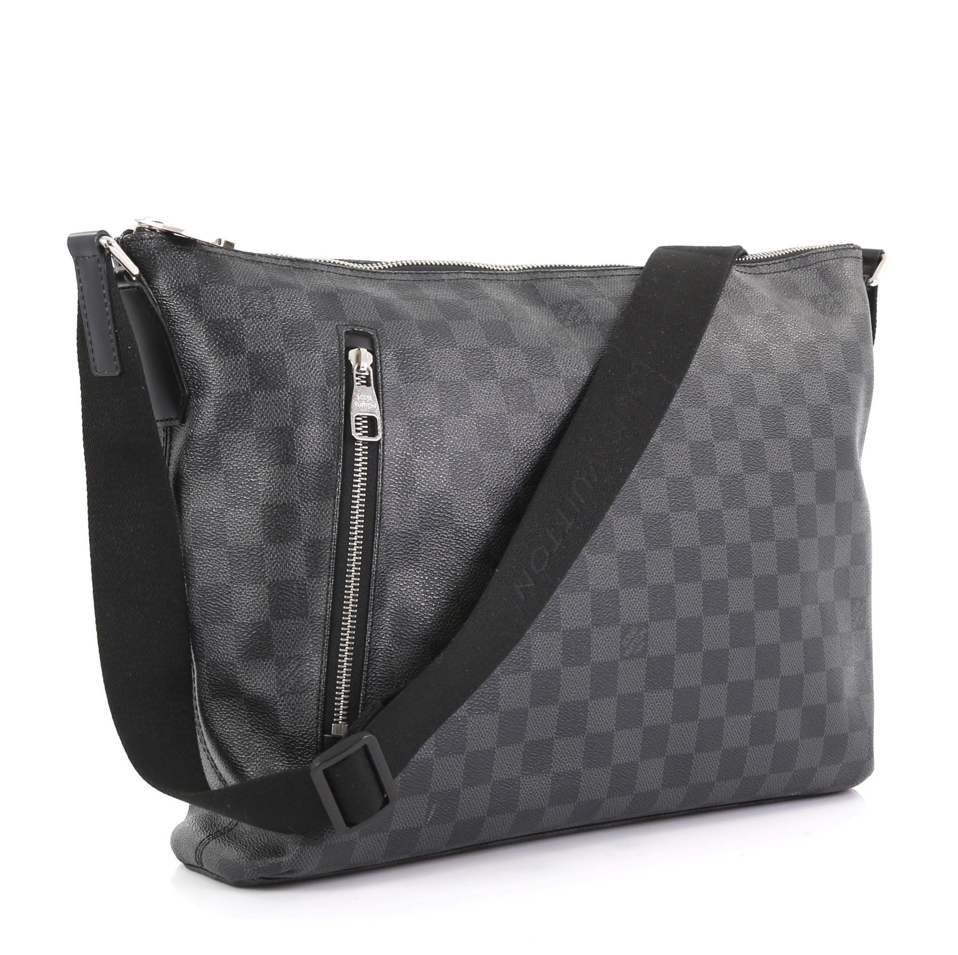 This Louis Vuitton Mick Handbag Damier Graphite MM, crafted from damier graphite coated canvas, features an adjustable shoulder strap, leather trim, exterior zip pockets, and silver-tone hardware. Its zip closure opens to black fabric interior with