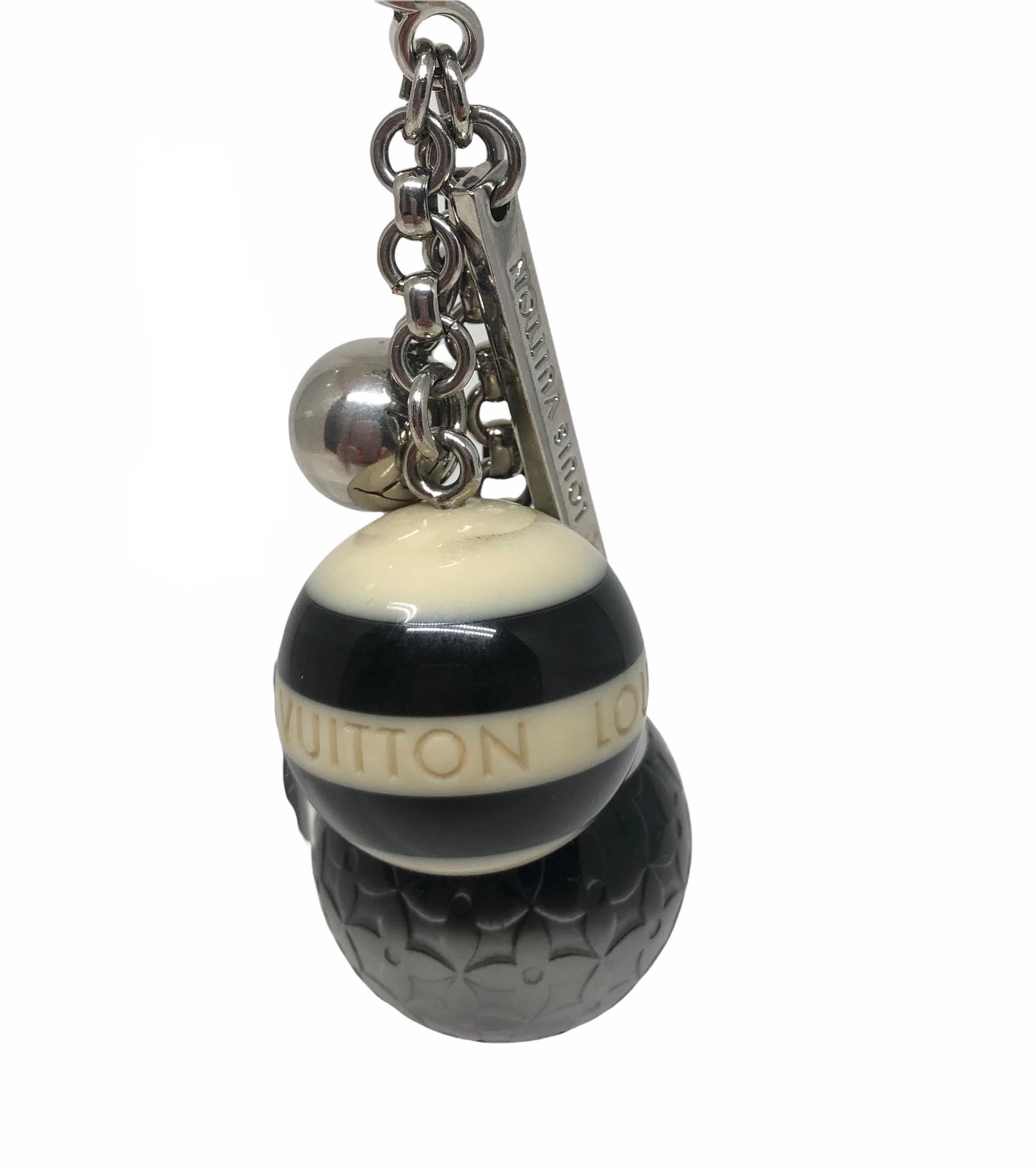 This cute charm and key  features two colored ball charms, a bigger pink ball with monogram flower print and a smaller pink one with stripes and Louis Vuitton signature. It also has one small golden ball charm with LV engraving and a thin metal