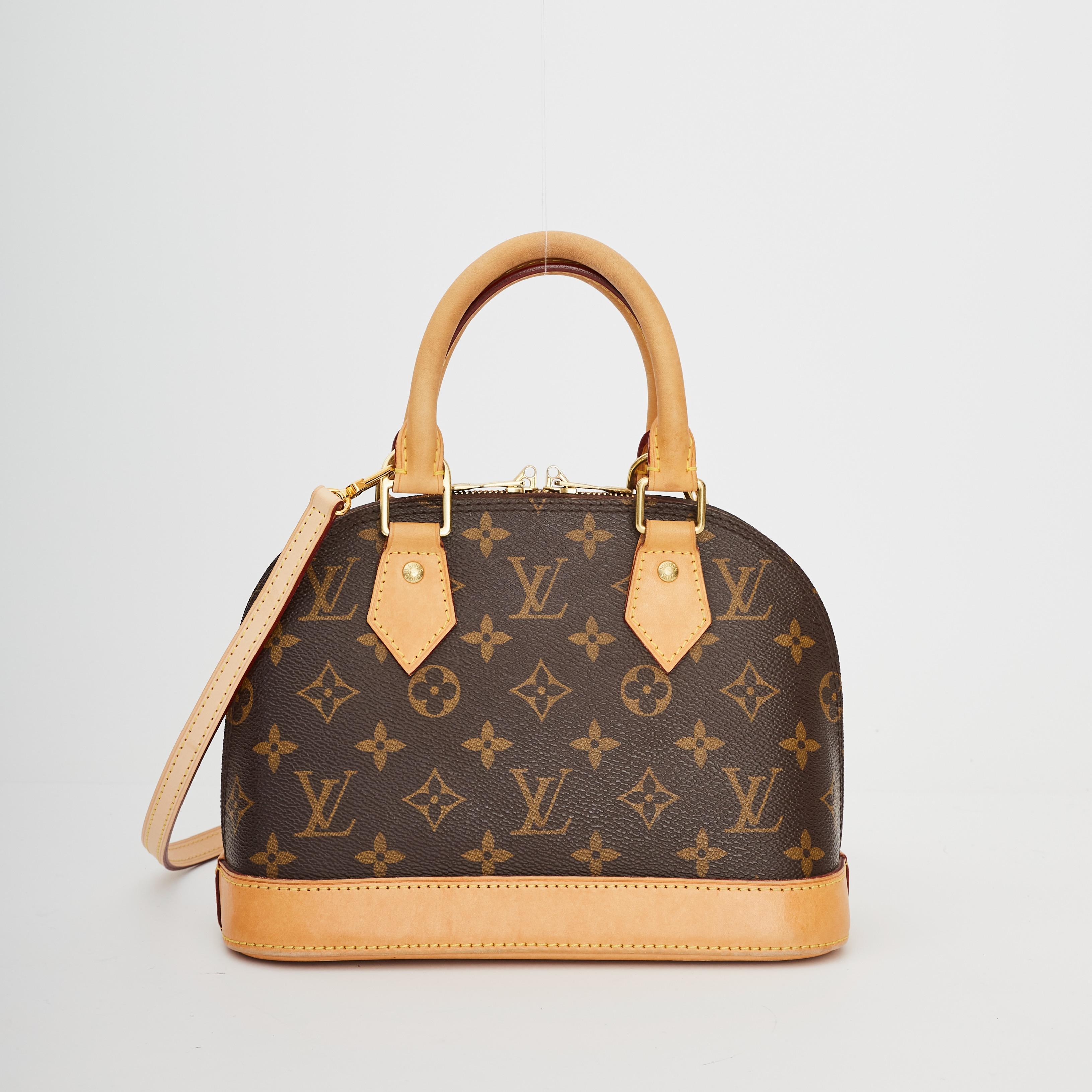 This small bag is made of Louis Vuitton monogram coated canvas. The bag features vachetta cowhide leather trim including a solid base, rolled leather top handles, and optional shoulder strap, and brass hardware. The top zippers open to a fabric