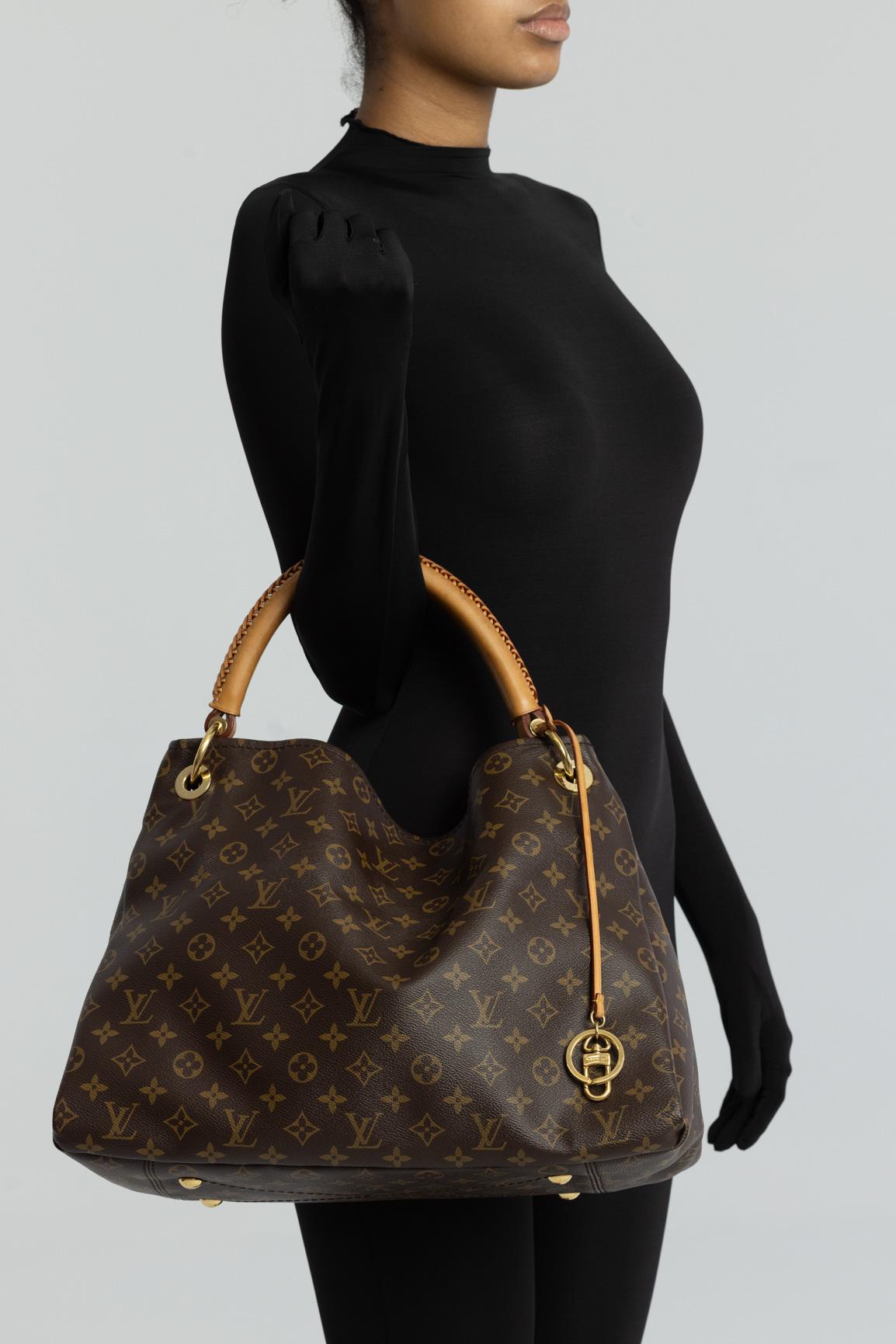 LV Artsy MM. This large tote is made of Louis monogram coated toile canvas. with leather finishes. The bag features a natural vachetta cowhide rolled leather handle with a sleek braided accent, an open, an ivory microfiber interior and an interior