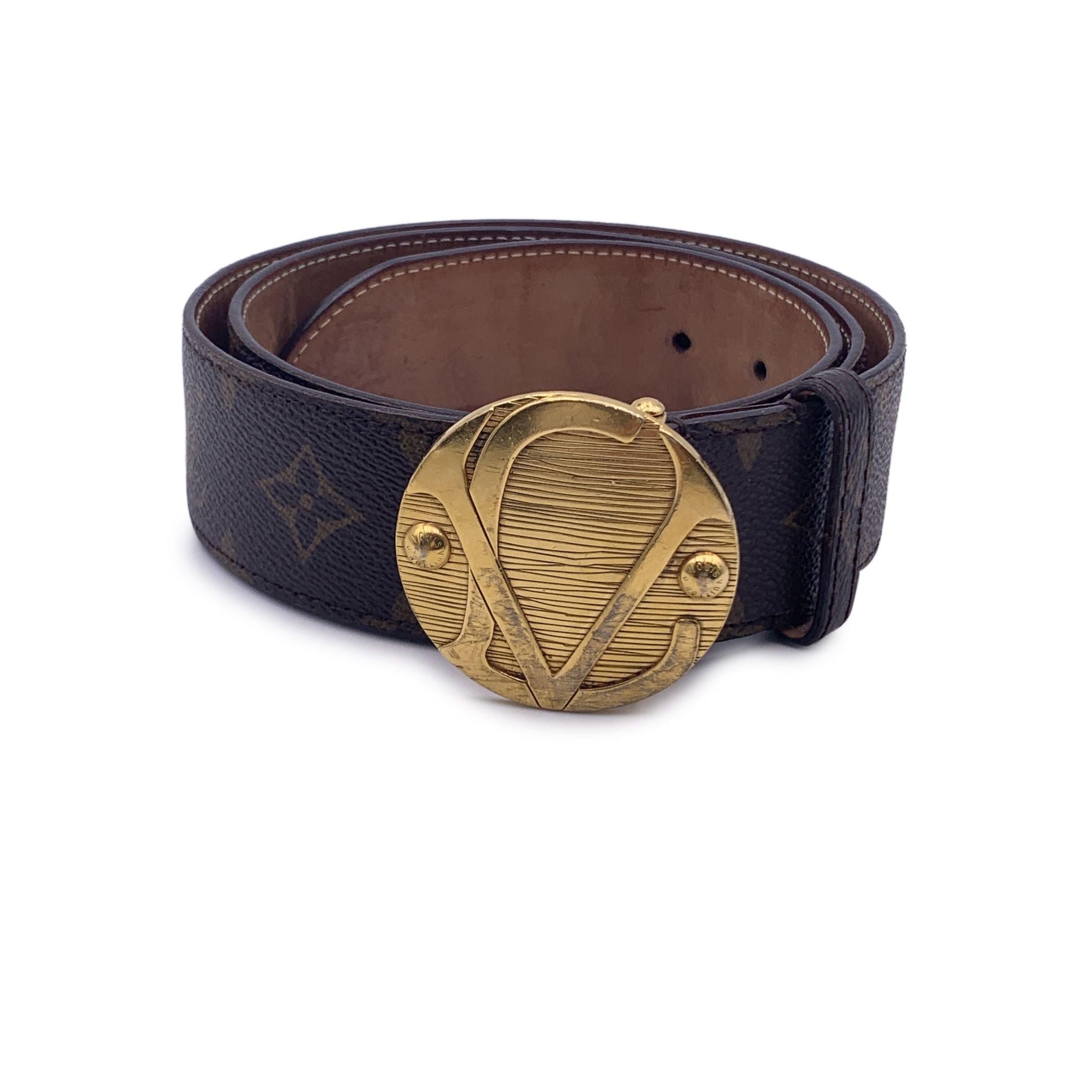 LOUIS VUITTON Ceinture 1904 monogram belt. The round gold metal buckle with LV logo is inspired by the lock of a Louis Vuitton trunk made in 1904. Five holes adjustment. Width: 1.5 inches - 4 cm. Total length: 40 inches - 101.6 cm (only strap -