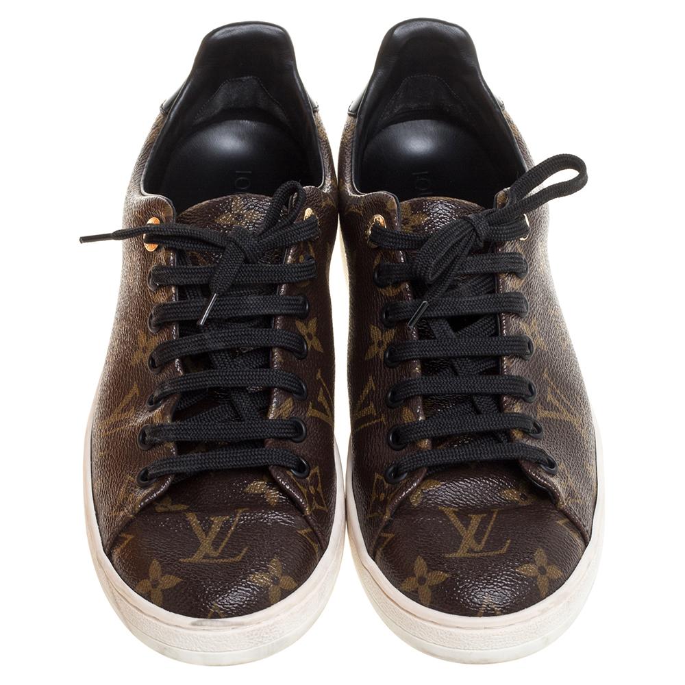 Team this trendy Louis Vuitton low top sneakers with your casual outfits. Crafted in Italy, they are made from the brand's signature Monogram canvas and black patent leather. They are styled with lace-up fronts, round toes, gold-tone hardware, and