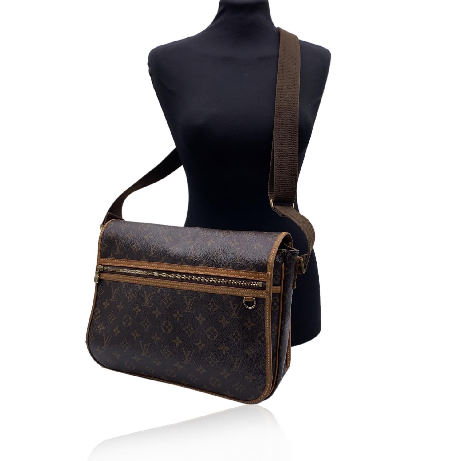 LOUIS VUITTON 'Bosphore MM' crafted in timeless monogram canvas with vacchetta leather trim. Flap with magnetic hidden closure. It features 1 large zip pocket on the front and a D-Ring. Golden brass hardware and adjustable canvas shoulder strap. 1