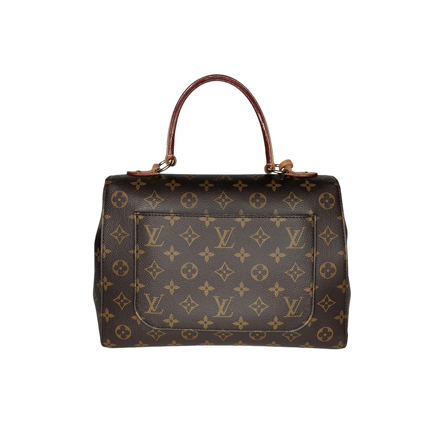 Louis Vuitton Cluny MM Top Handle Bag By Nicolas Ghesquière. This lovely handbag is crafted of monogram toile canvas. The handbag features a vachetta top handle and brass hardware. The flap opens to a twill fabric interior with patch pockets and a