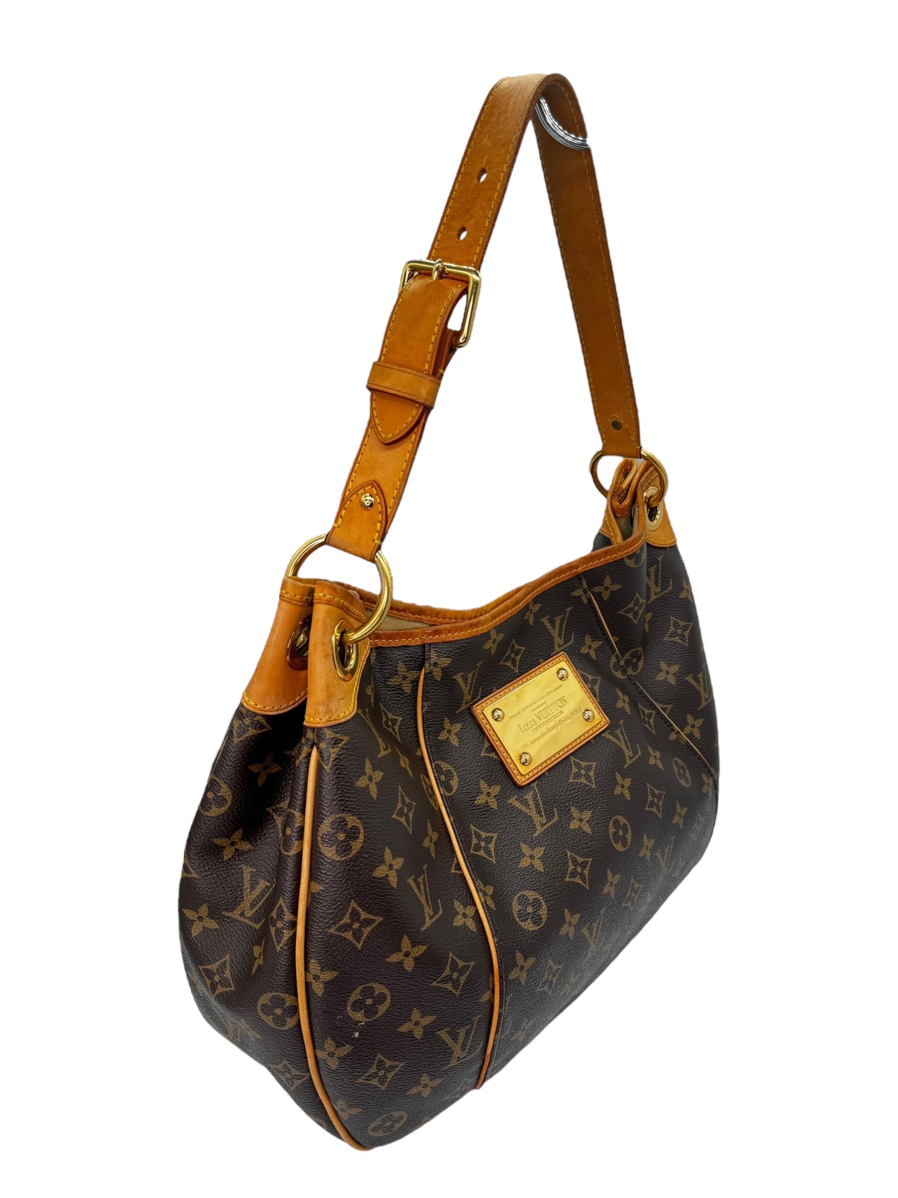 This stylish shoulder bag is finely crafted of classic Louis Vuitton monogram on toile canvas. It features an adjustable vachetta leather shoulder strap, vachetta leather piping and trim complete with polished brass hardware including a large