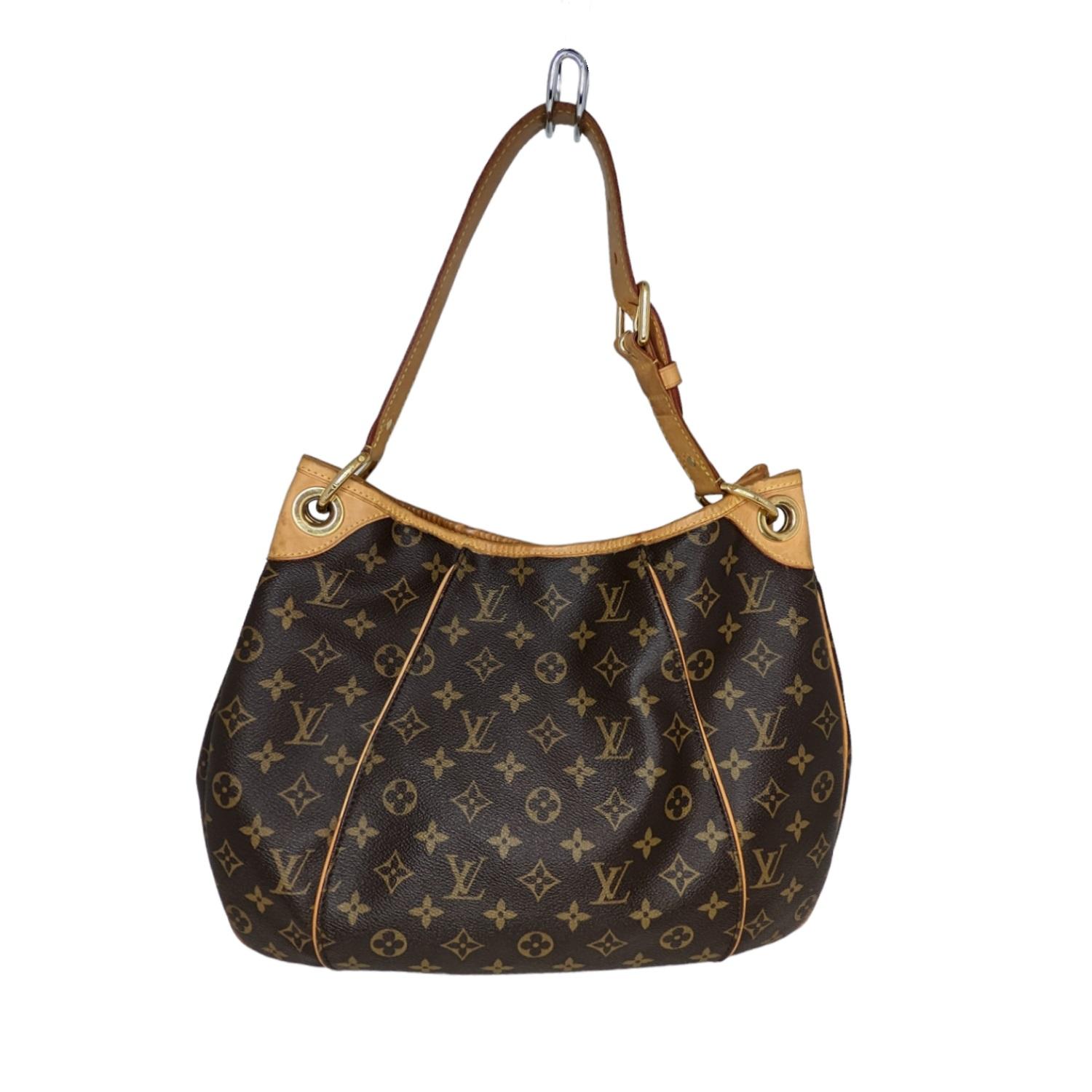 This fashionable hobo style handbag is crafted of Louis Vuitton's signature monogram canvas in brown. It features a vachetta cowhide leather looping shoulder strap, piping, trim, and brass hardware. The top opens to a beige microfiber interior with