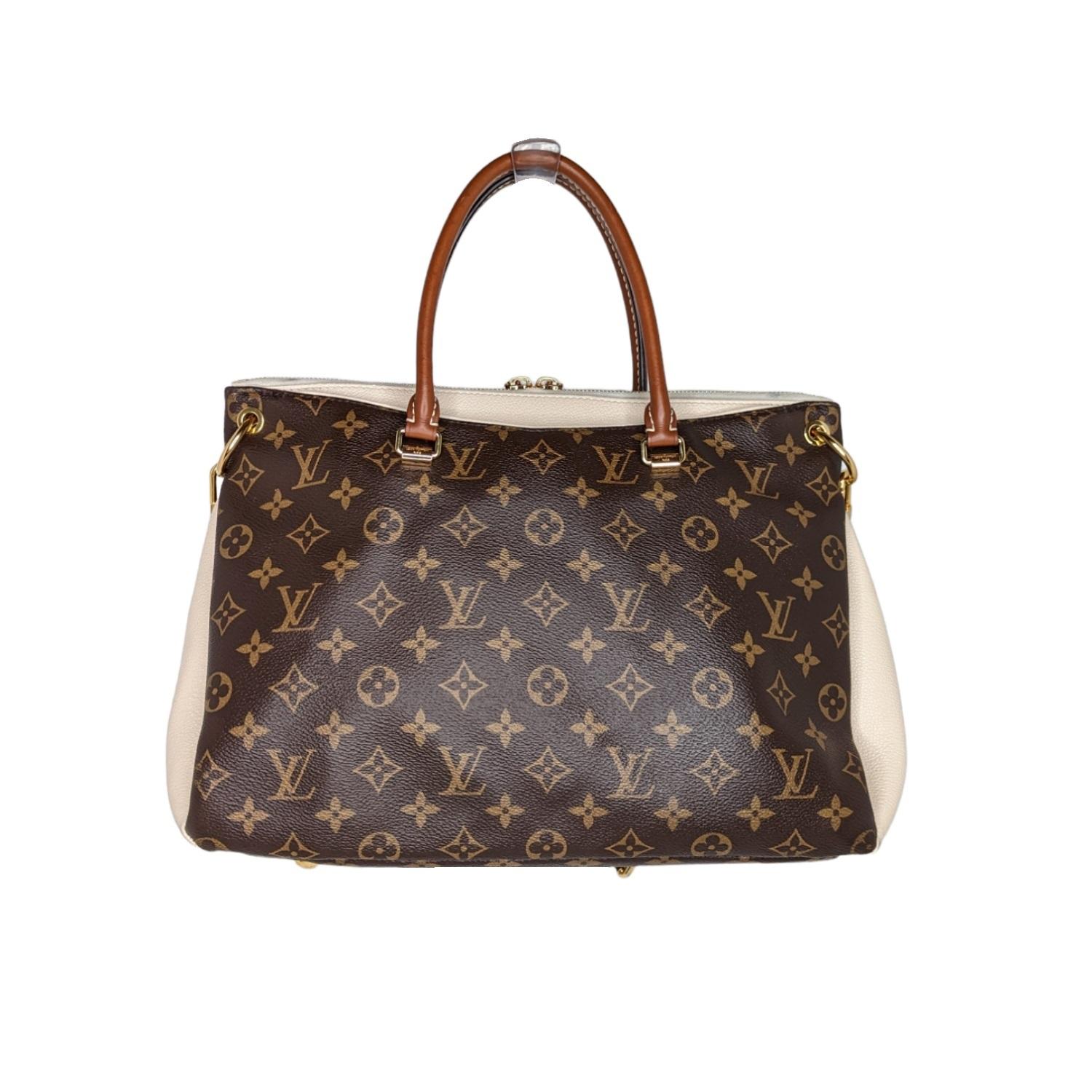 Brown and tan monogram coated canvas Louis Vuitton Pallas tote with brass hardware, single flat shoulder strap featuring buckle adjustment, dual rolled top handles, tan Vachetta and creme leather trim, protective feet at base, dual exterior pockets