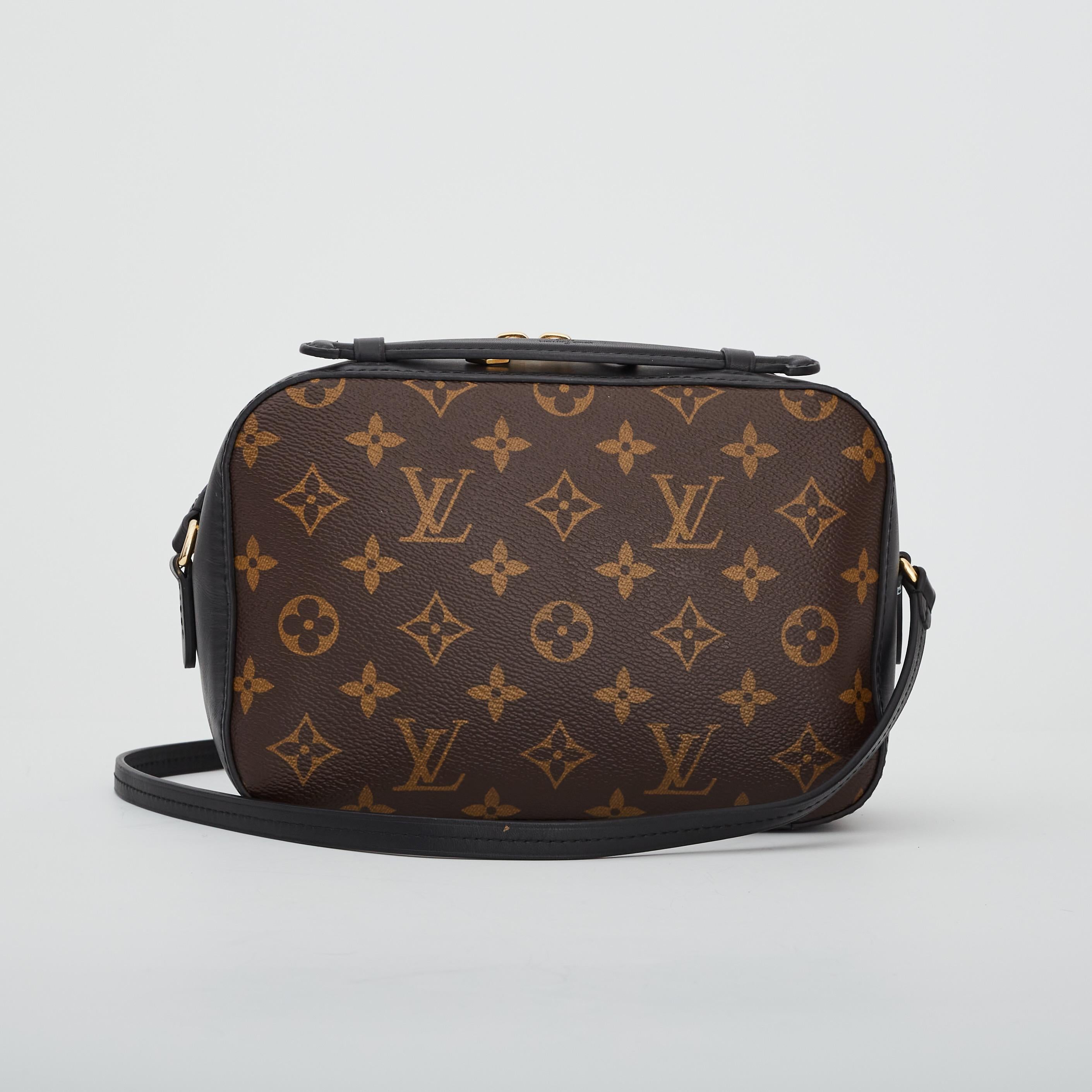 This Saintonge crossbody bag is from the house of Louis Vuitton. It is made from brown monogram coated canvas and is trimmed with black leather. The front of the bag is highlighted with a gold-tone accent attached with leather tassels for some extra