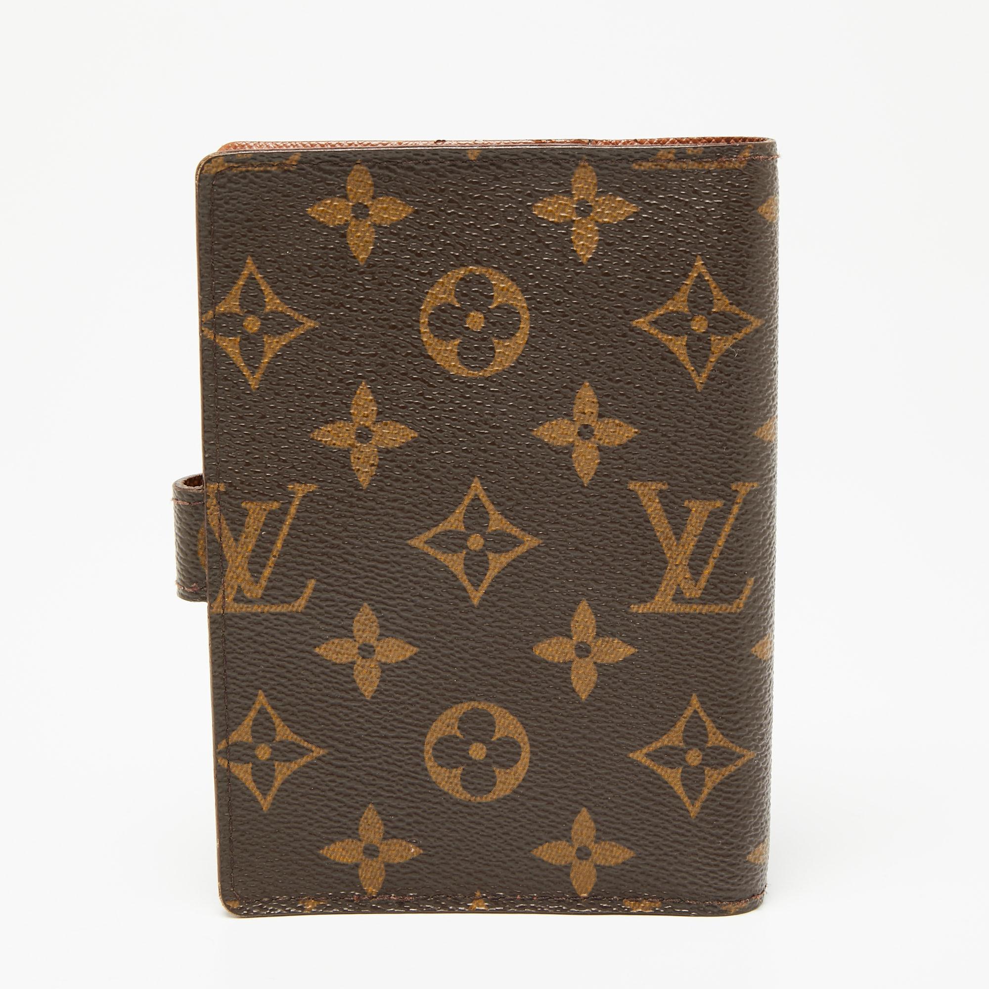 Combining the luxurious touch with utility, this Louis Vuitton agenda cover comes crafted from coated canvas in brown. It is designed with a snap button closure and an interior housing space for papers and slots for cards.

