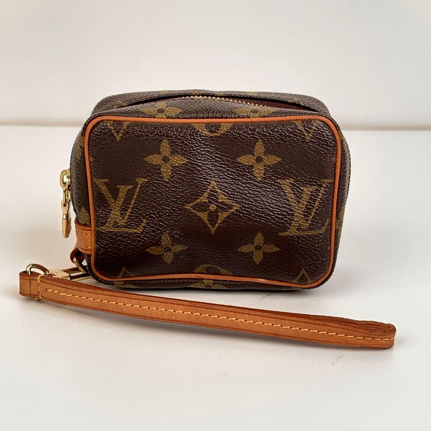 Louis Vuitton Monogram Canvas Trousse Wapity Mini multifunctional pouch. Monogram canvas with natural cowhide leather trim. Golden brass hardware. Leather wrist strap. Red microfiber lining. 'Louis Vuitton Paris - Made in France' embossed inside.
