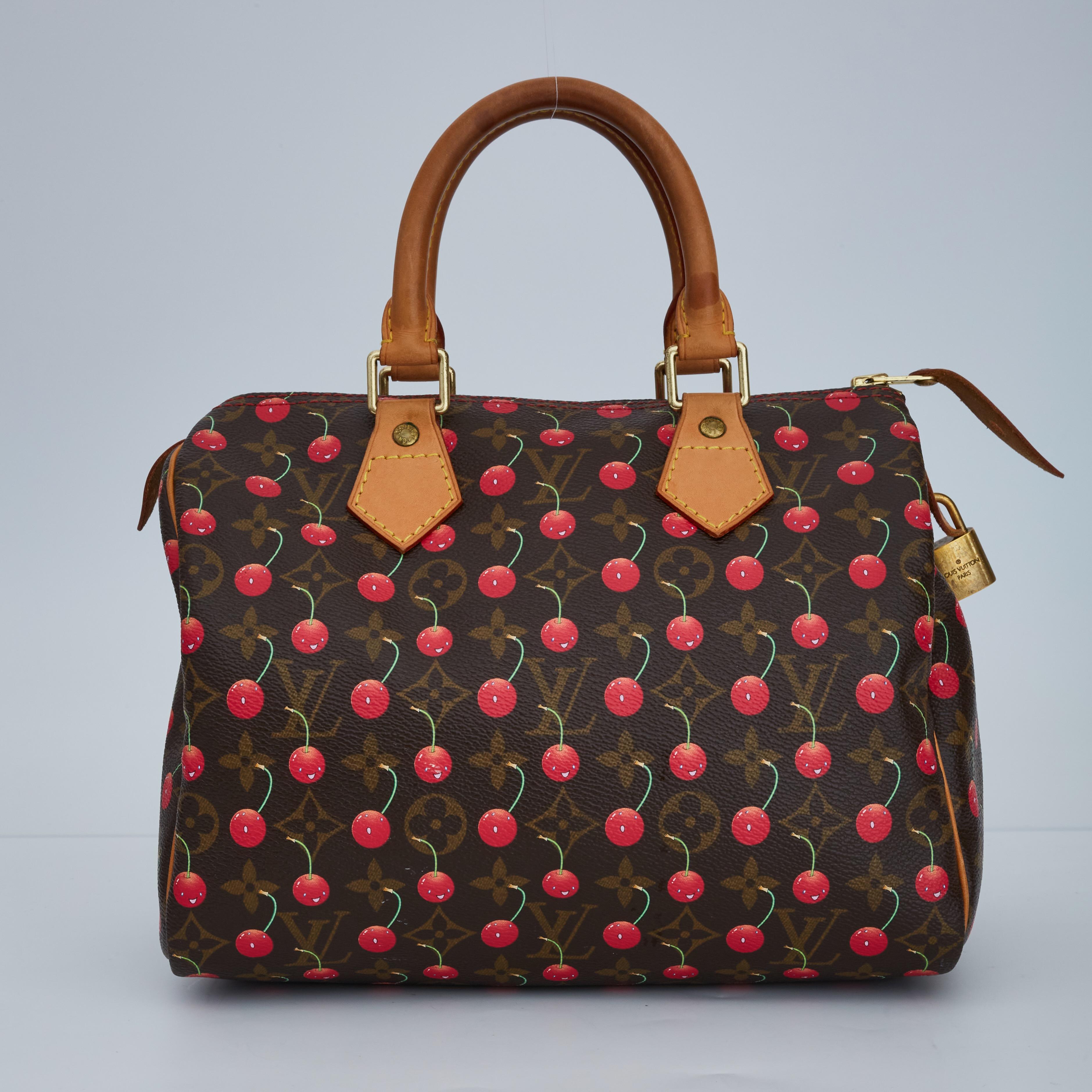 This handbag is made of traditional monogram coated canvas with an overlay of smiling cherries. The bag features rolled vachetta top handles, piping on the borders of the bag, gold hardware, top zip closure and a cocoa brown fabric interior with a