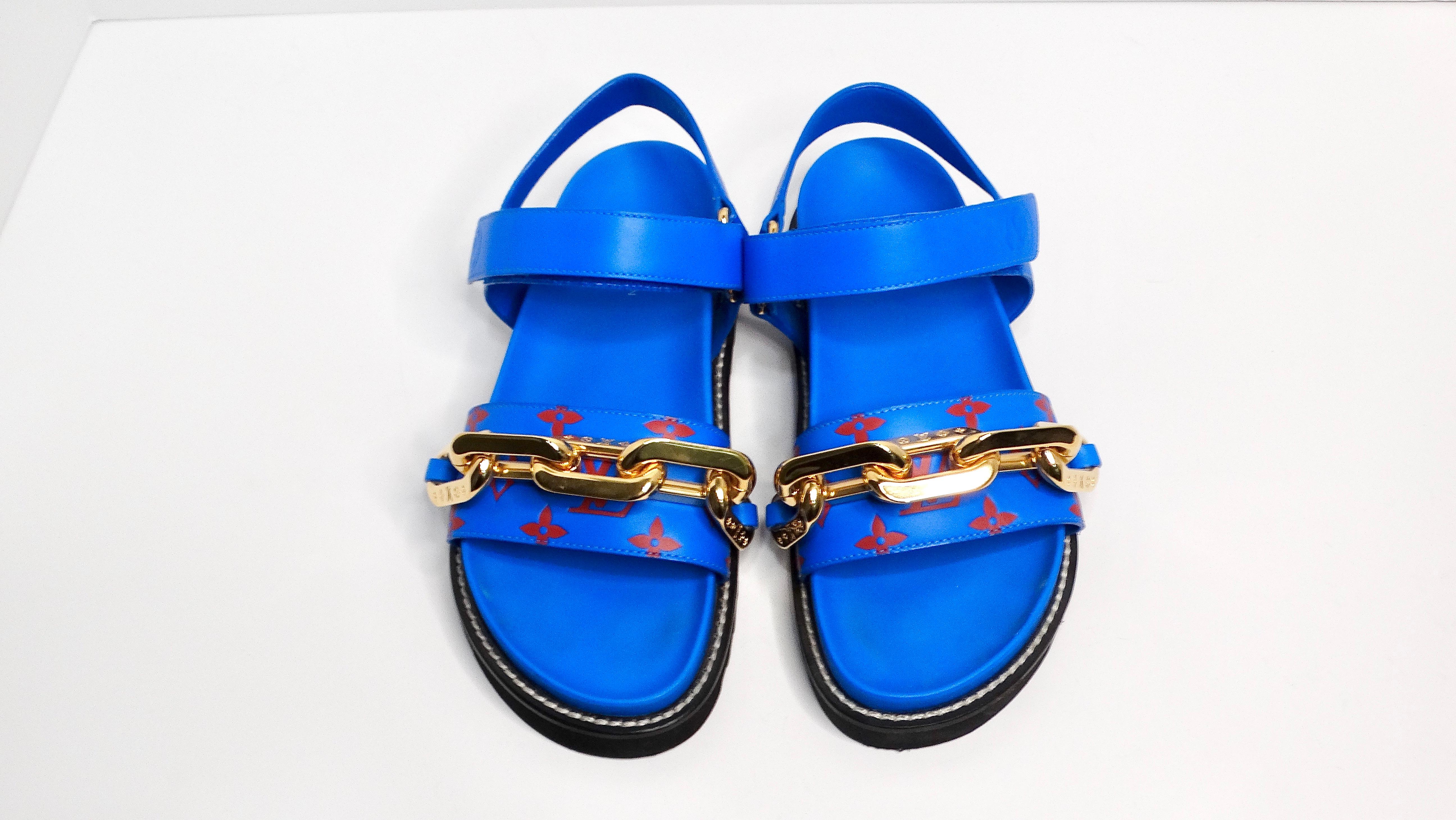 The Louis Vuitton Monogram Chain Strap Blue & Red Leather Sandals are a bold and stylish addition to any wardrobe. Featuring an electric blue base adorned with the iconic red LV monogram, these sandals exude luxury and flair. The chunky gold-toned