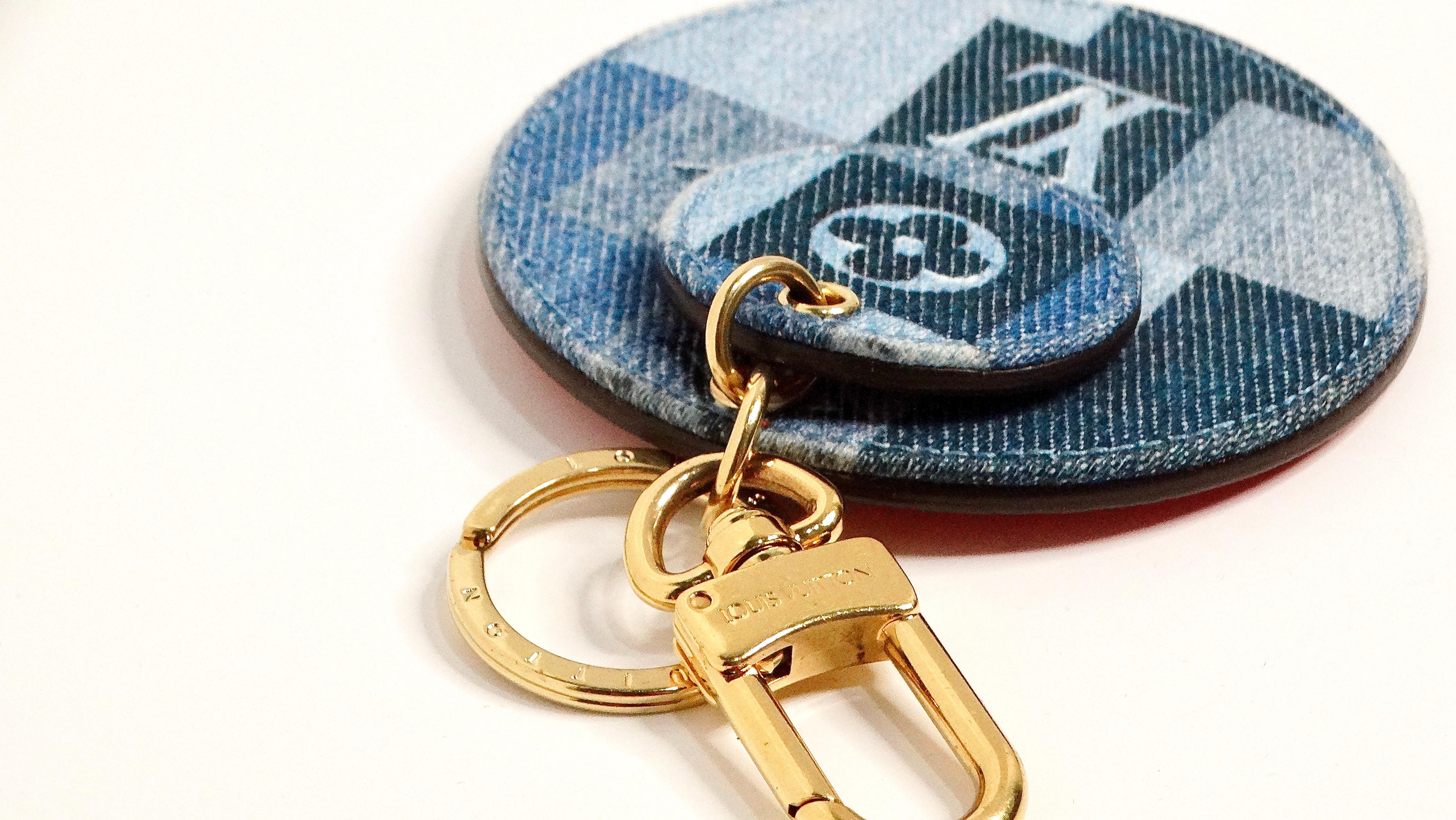 Il charm per borsa Louis Vuitton Monogram Denim con hardware dorato è un accessorio versatile ed elegante che aggiunge un tocco di lusso a qualsiasi borsa. Questo affascinante pezzo presenta due disegni circolari, uno più grande e uno più piccolo,