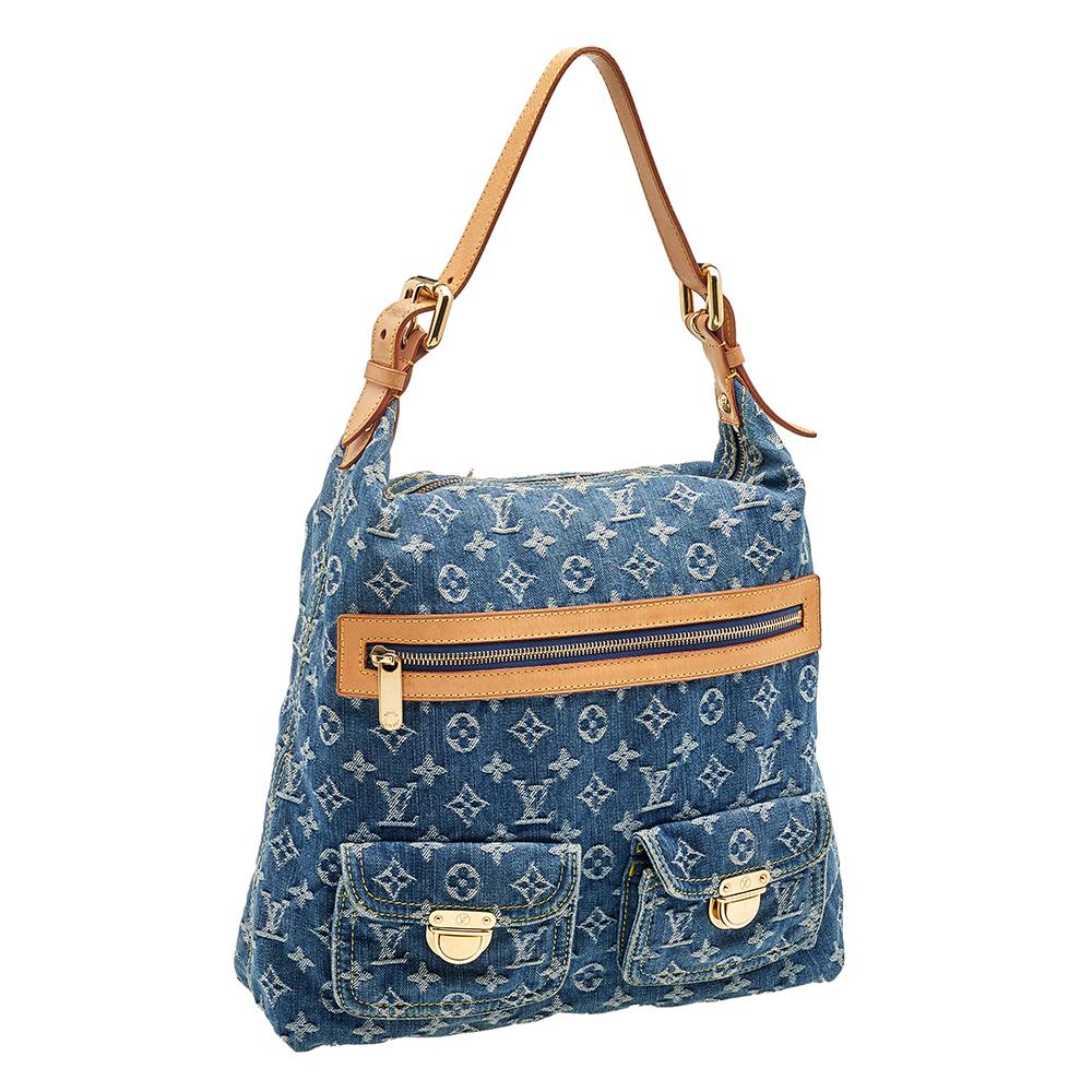 Complete your look with this stylish Baggy GM bag from Louis Vuitton. Crafted in France, it is made from blue monogram denim and leather. This beautiful bag features an adjustable flat leather handle and pockets at the front. The top zip closure