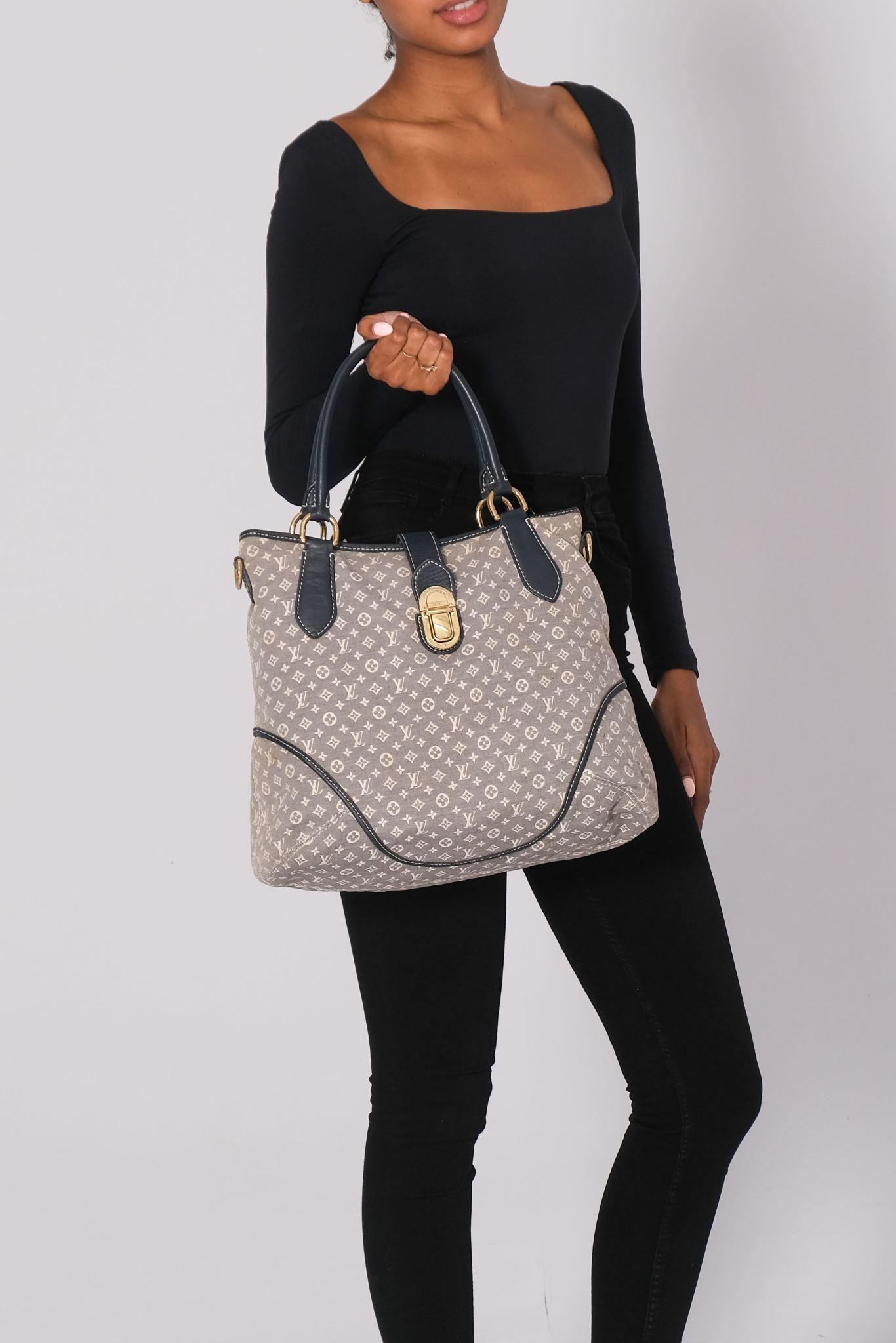 This tote has a classic look and is made of Louis Vuitton monogram denim canvas in ivory on blue. The bag features rolled leather top handles with brass links and an optional shoulder strap with brass clasps and a cross-over leather strap with a