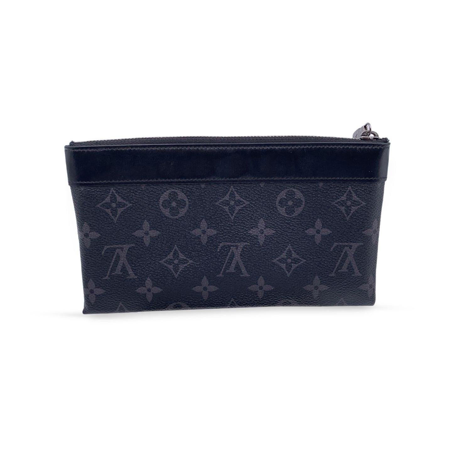 This beautiful Bag will come with a Certificate of Authenticity provided by Entrupy. The certificate will be provided at no further cost LOUIS VUITTON 'Pochette Discovery' clutch in Eclipse monogram canvas. Silver metal D-ring on the front. Upper