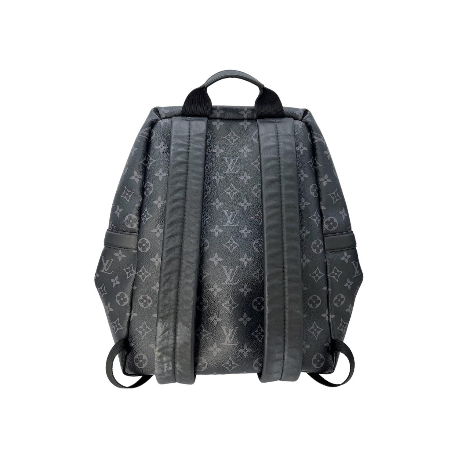 This Louis Vuitton Discovery Backpack was made in France and it is finely crafted of the Louis Vuitton Monogram Eclipse coated canvas with leather trimming and silver-tone hardware features. It has a frontal slip pocket with a magnetic closure along