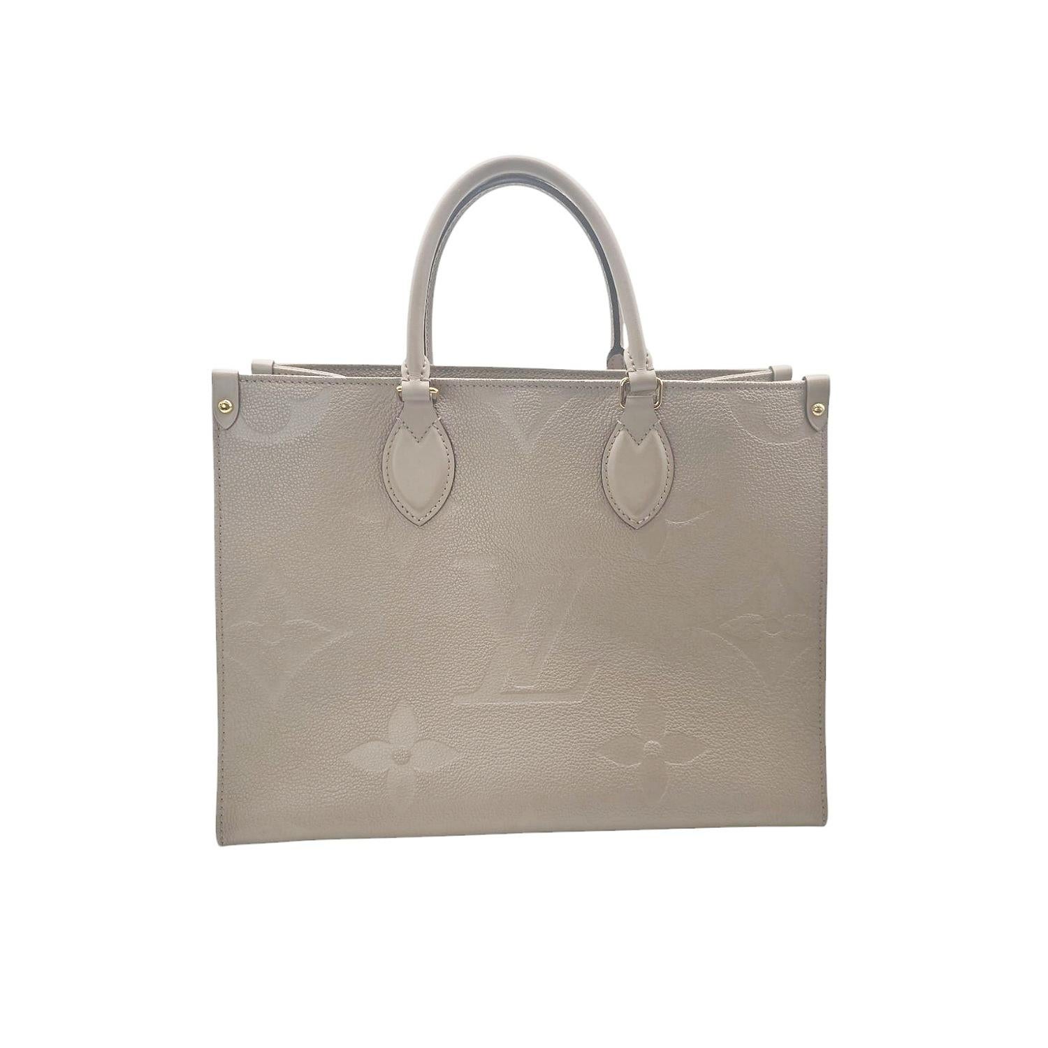 Ce MM Empreinte Monogram Giant Onthego de Louis Vuitton est confectionné en cuir de veau Tourterelle taupe avec l'impression surdimensionnée du monogramme Louis Vuitton embossé. Le sac est doté d'anses supérieures en cuir roulées, de bandoulières