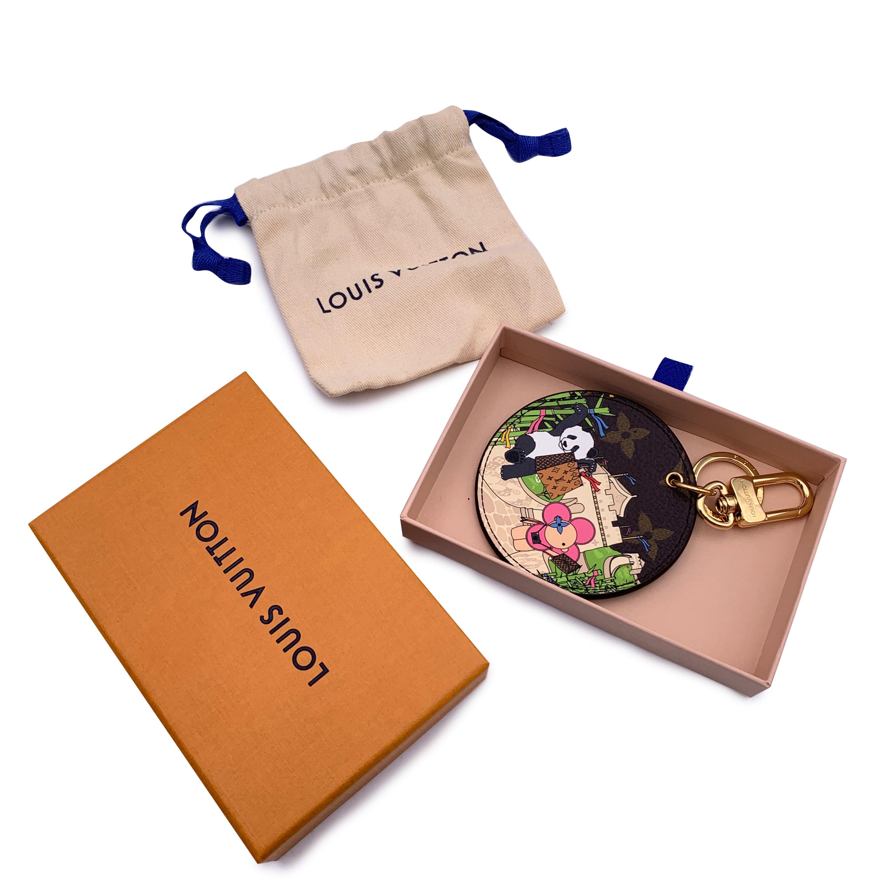 Louis Vuitton China Wall Key Holder/Bag Charm. It features a colorful illustration of the LV mascot Vivienne enjoying a walk in the Great Wall in China with a panda on a side. Light blue leather on the other side. Gold metal clasp and key ring. The
