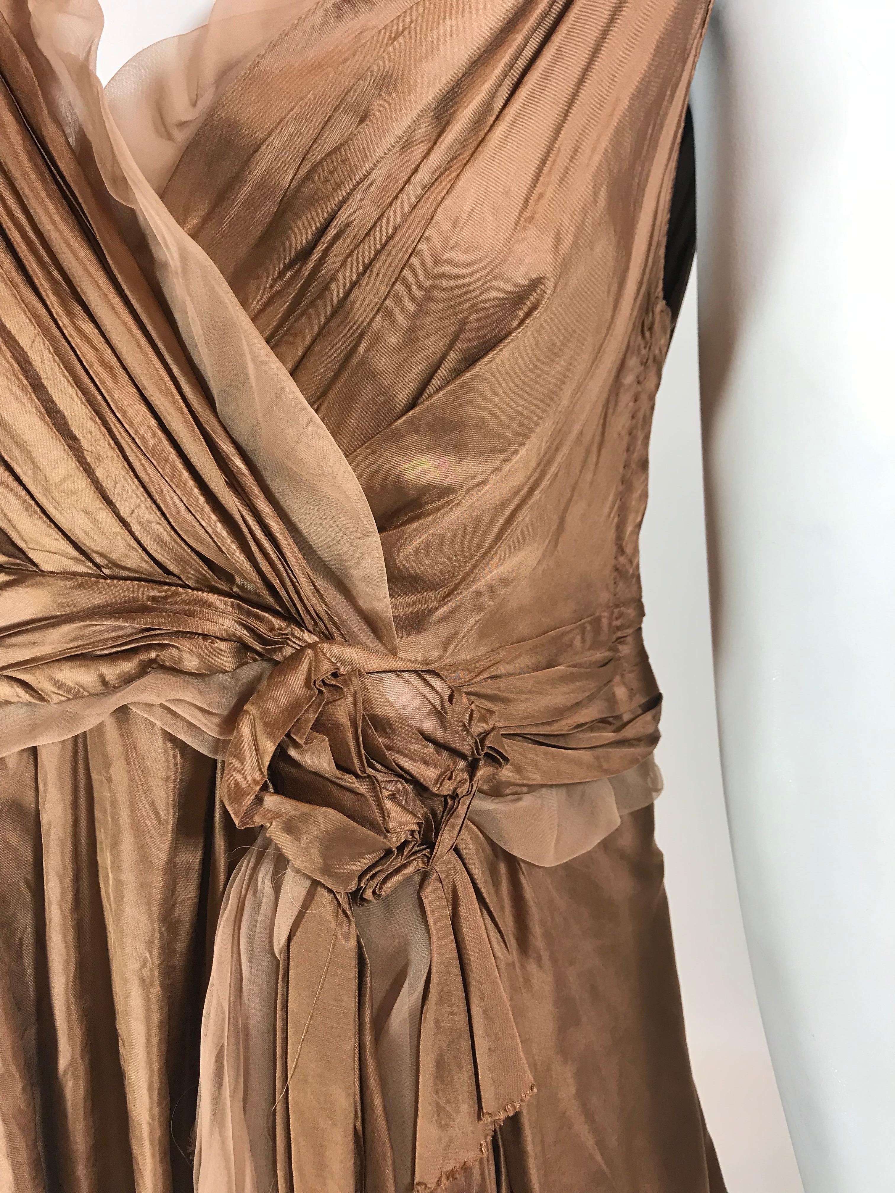Metallic rose gold-tone sleeveless A-line top with surplice neck, floral adornment at waist, tonal chiffon trim, Monogram lace trim at hem and concealed snap closures at side.