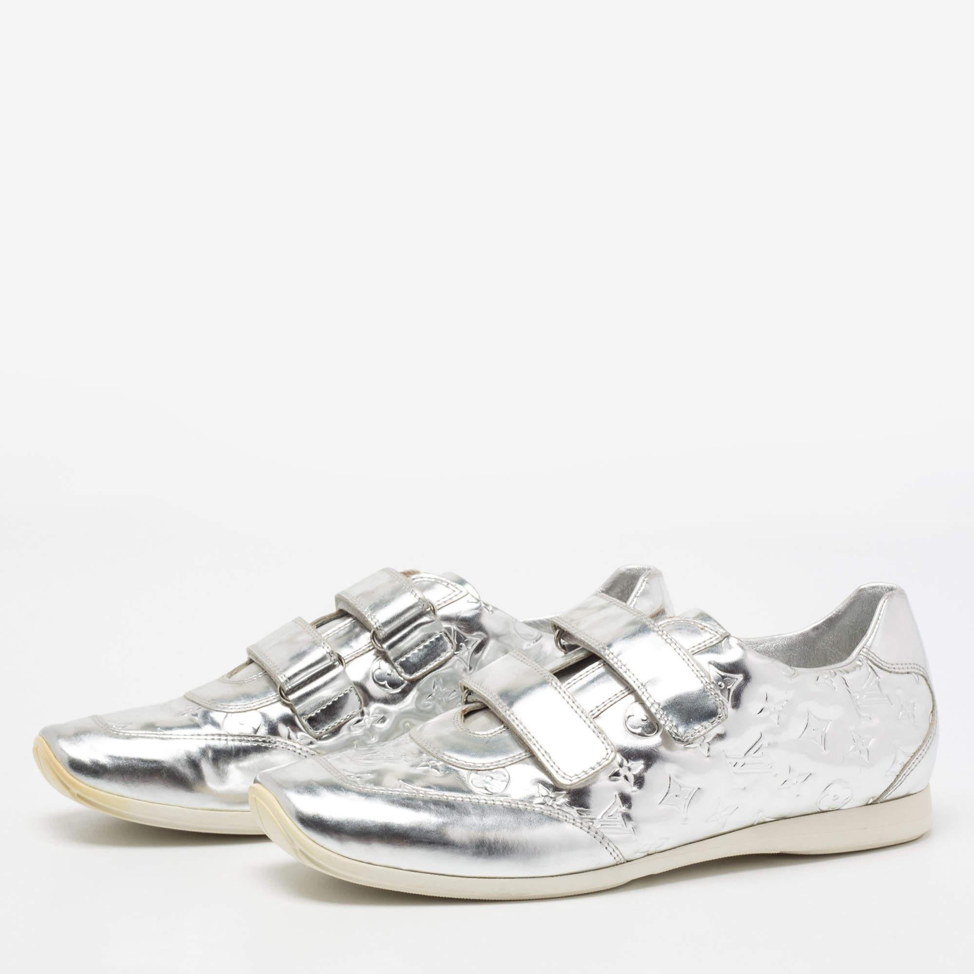 These glistening low-top sneakers from Louis Vuitton are here to elevate your style and let you explore new dimensions in fashion. The metallic silver shoes are created skillfully using Monogram leather with velcro-strap closures adorning the