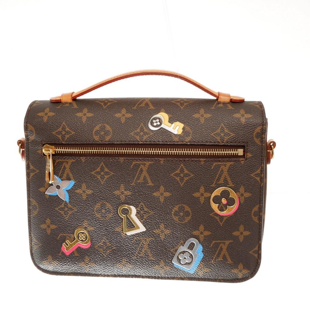 Brown and tan multicolor monogram love lock coated canvas Louis Vuitton Metis two way bag features one rear zip pocket at the back, flap top closure with iconic golden-tone LV S-lock, single flat leather top handle, two compartment with Alcantara