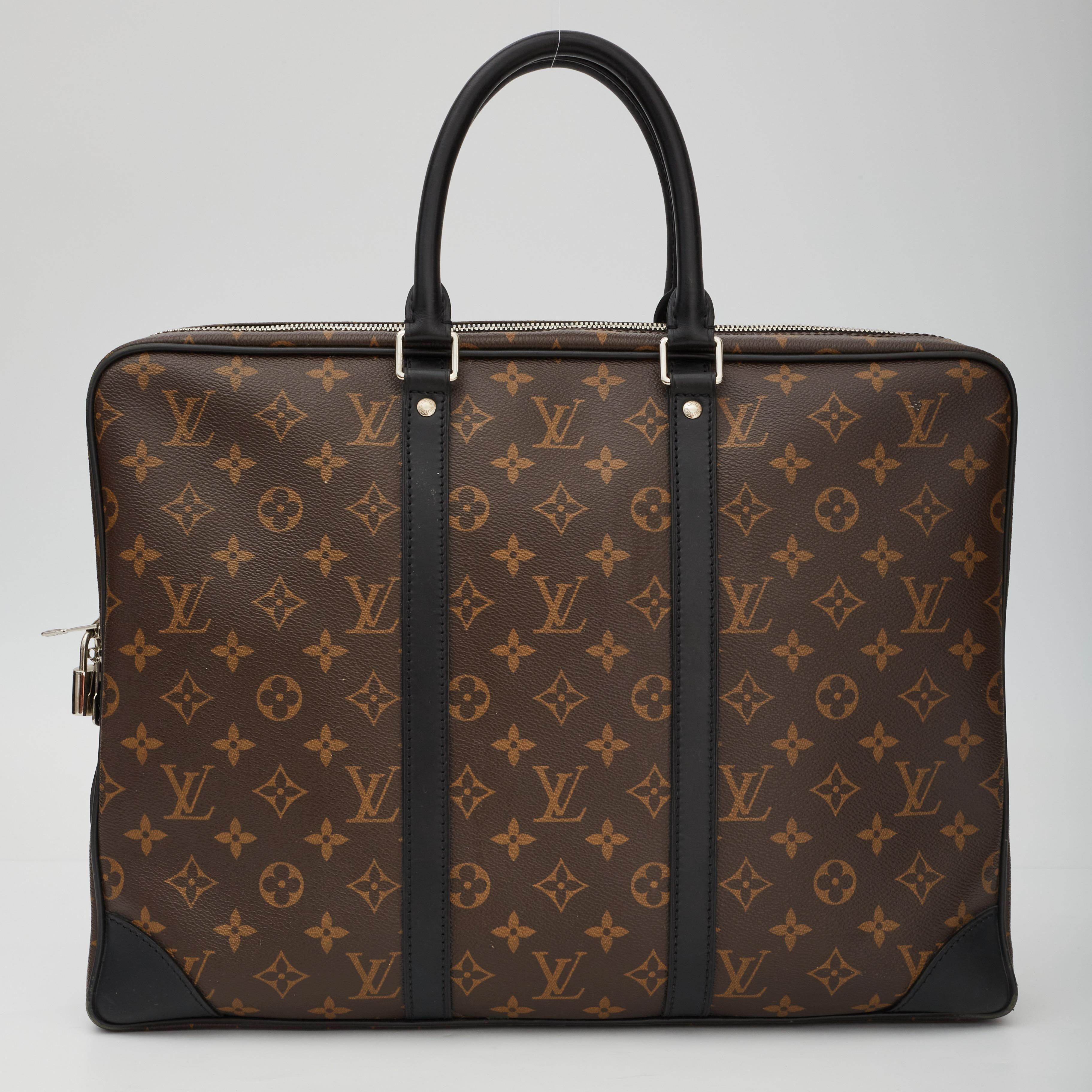 This bag is made with coated canvas with monogram print and features black cowhide leather trim, dual rolled leather top handles, polished silver hardware, top tip closure with double zip tabs and bordeaux lining with zipper and patch